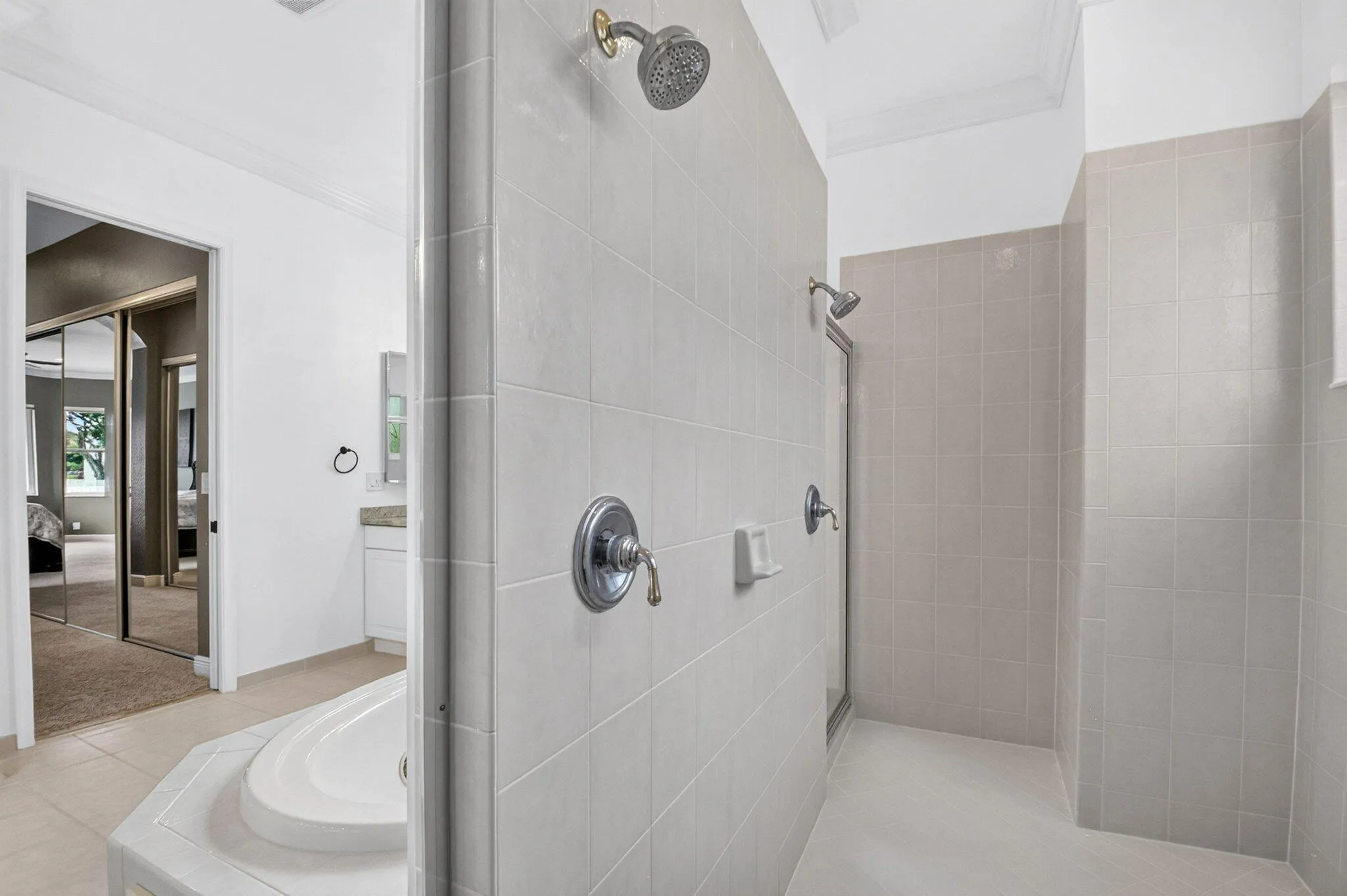 Tile-surround shower with dual shower heads, a built-in soap dish, and chrome fixtures