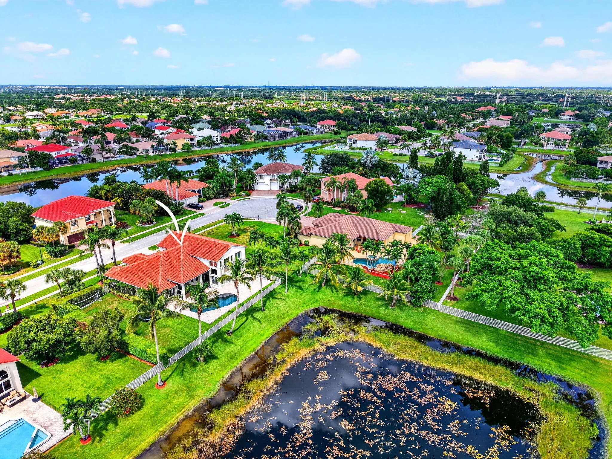 Red tile roof, private swimming pool, mature palm trees, white fence, waterfront property