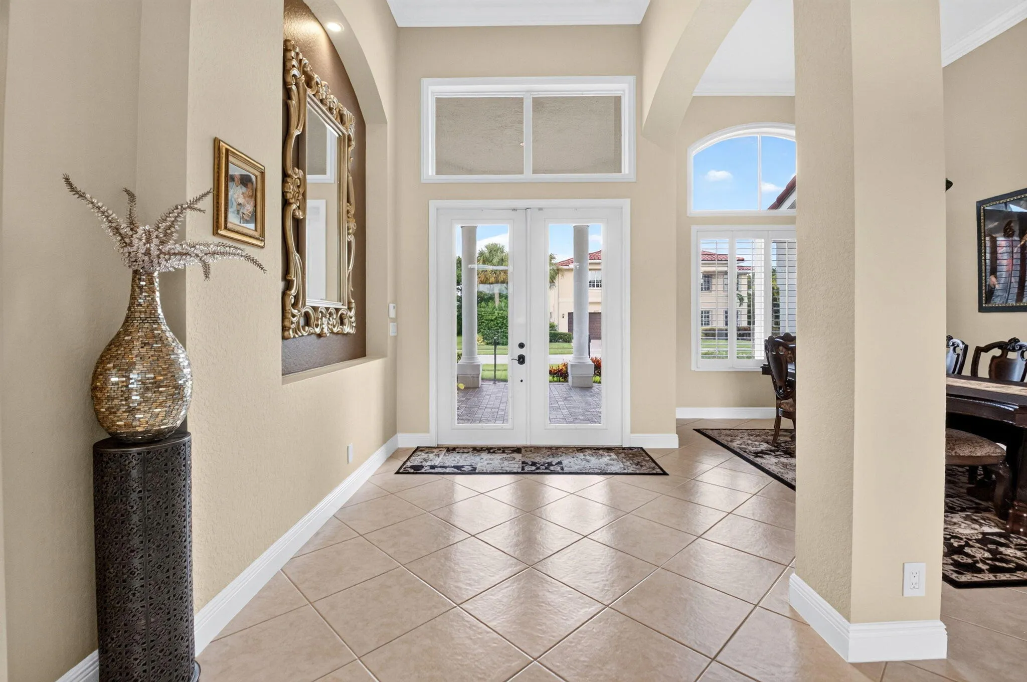 Double entry doors with glass panels, transom windows, arched openings, and diagonal tile flooring