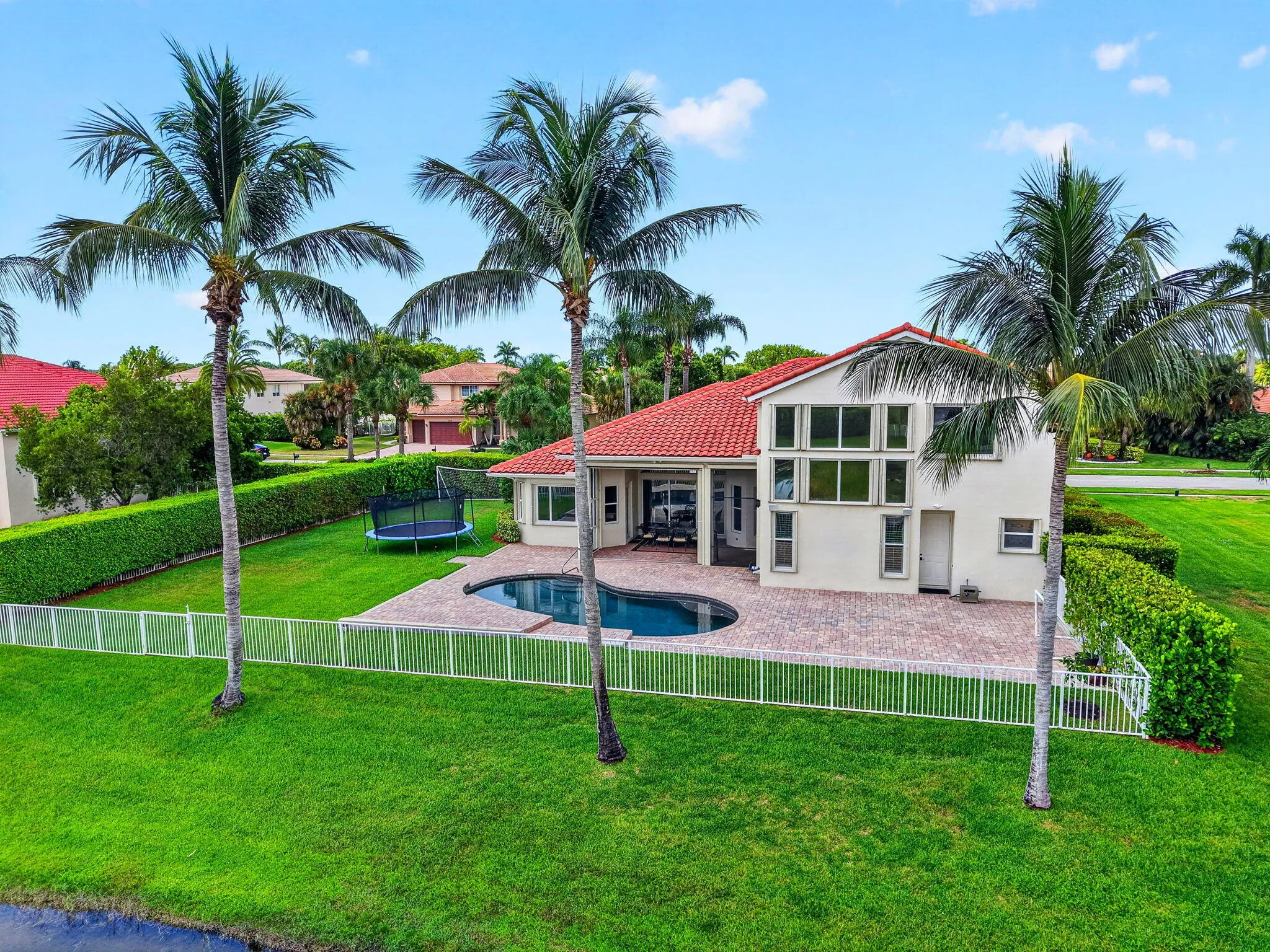 Exterior featuring a red tile roof, white stucco finish, and multiple large windows
