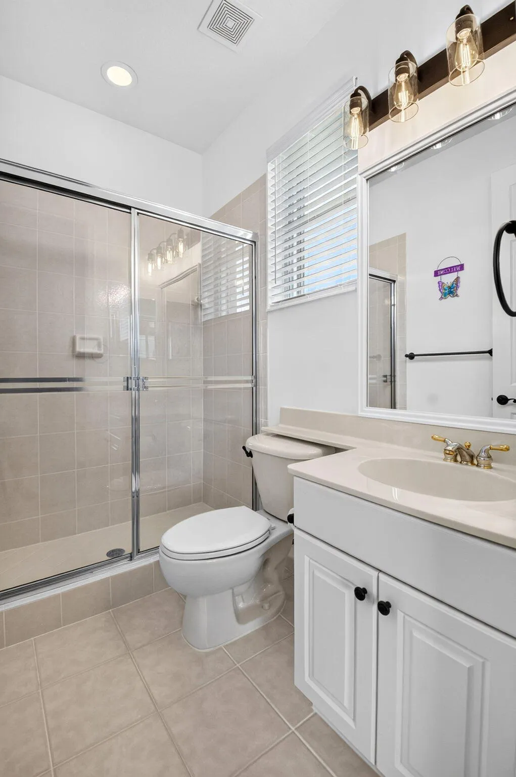 Glass-enclosed shower, white vanity with cabinet storage, tile flooring, and a single basin​​‌​​​​‌​​‌‌​‌‌​​​‌‌​‌​‌​‌​​​‌​​ sink