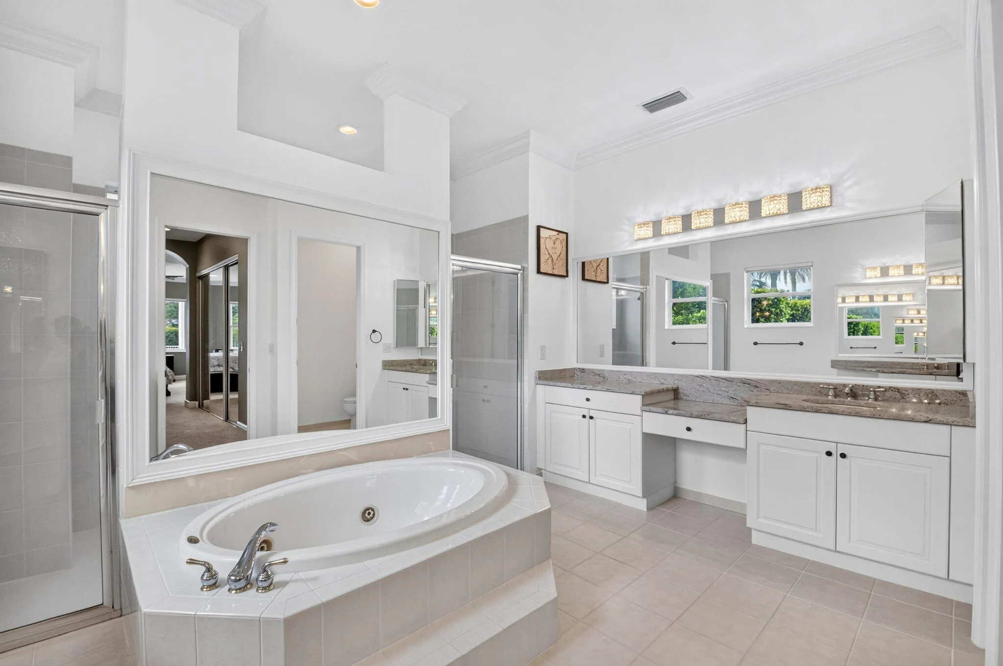 Built-in soaking tub with tile surround, dual vanity with undermount sinks, and separate shower enclosure