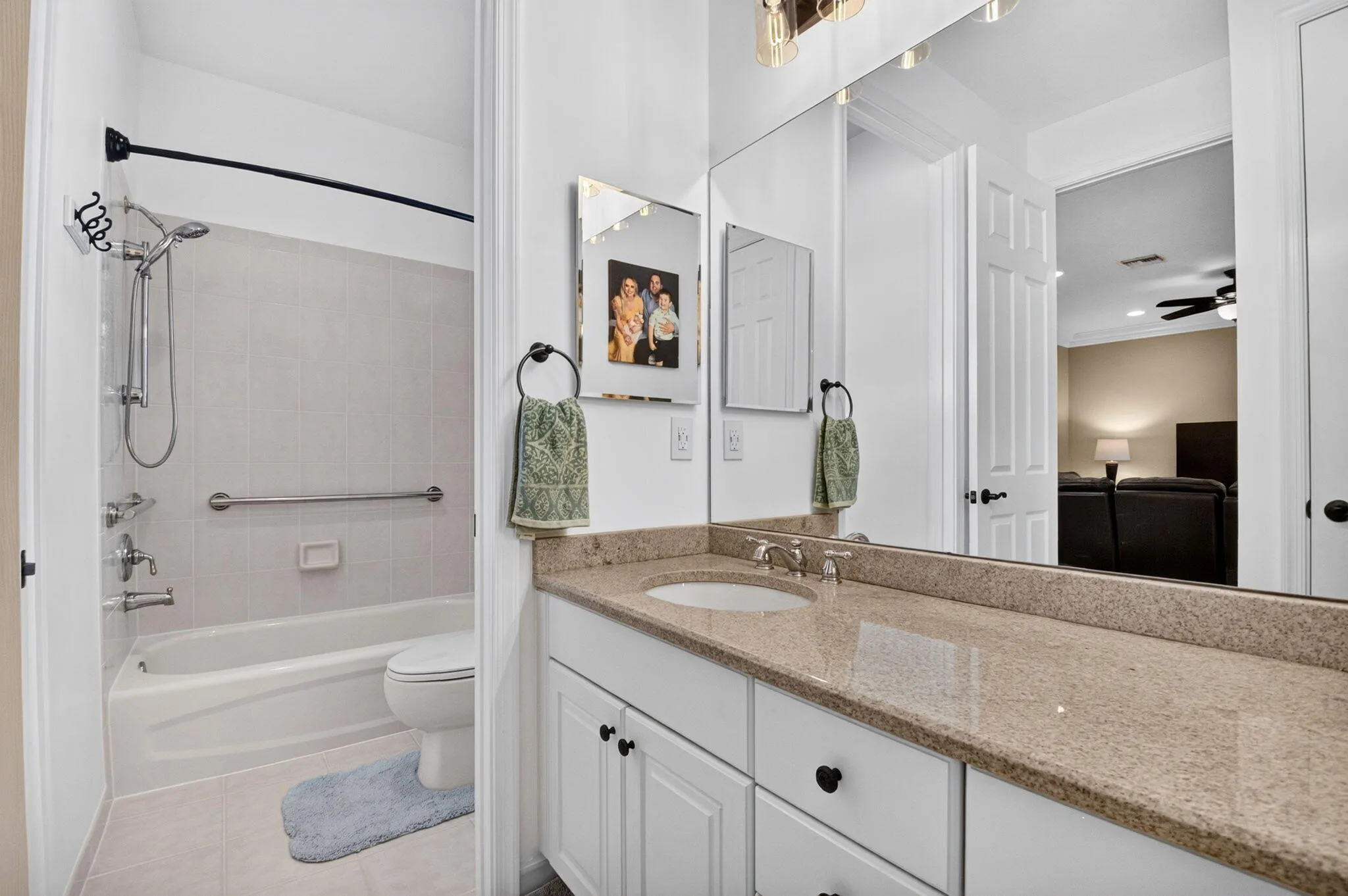 Bathroom featuring a single vanity with a solid surface countertop, an undermount sink, and white cabinetry