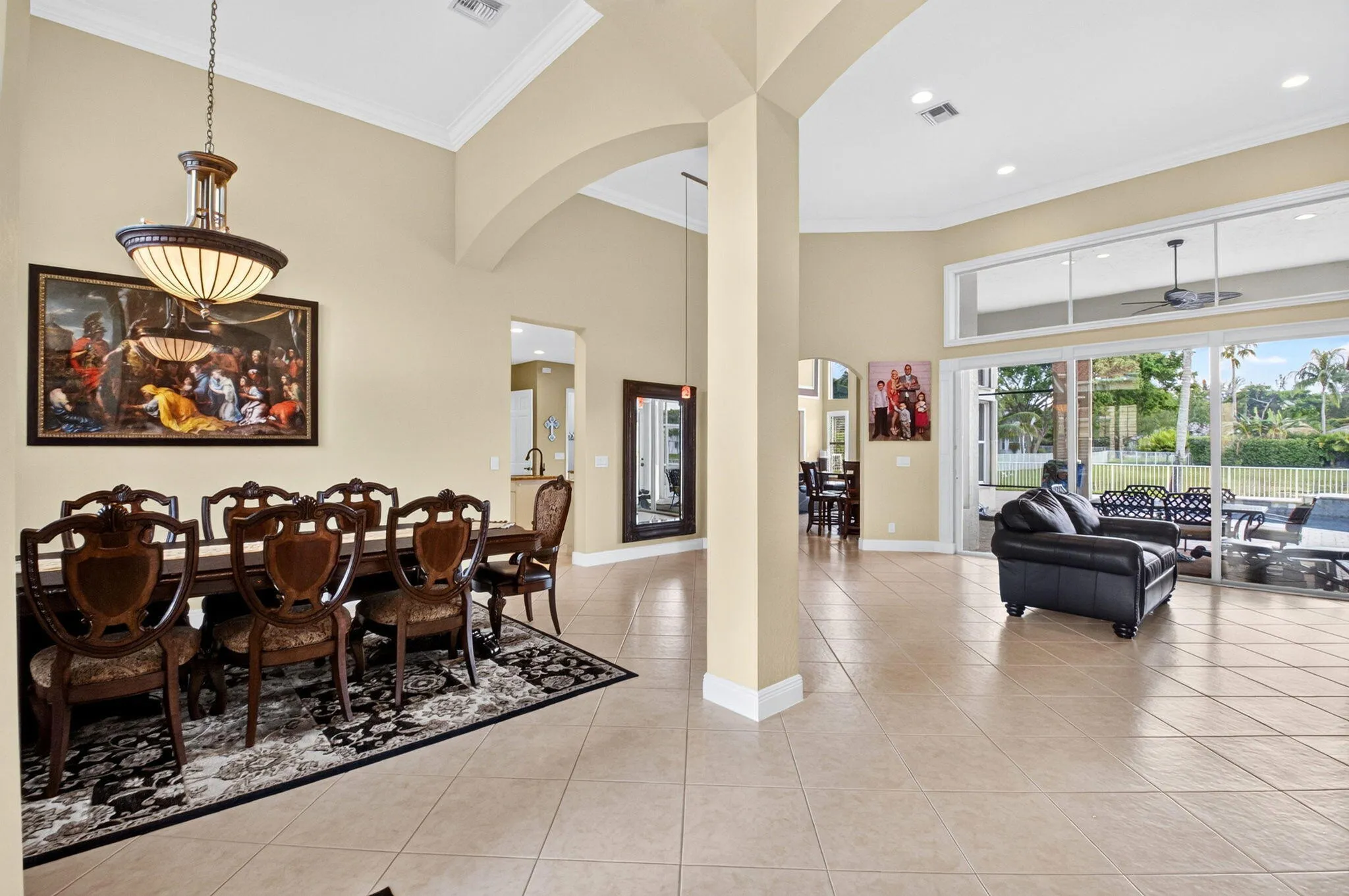 Tile flooring throughout, vaulted ceilings with crown molding, transom windows, and glass sliding doors leading to an exterior patio