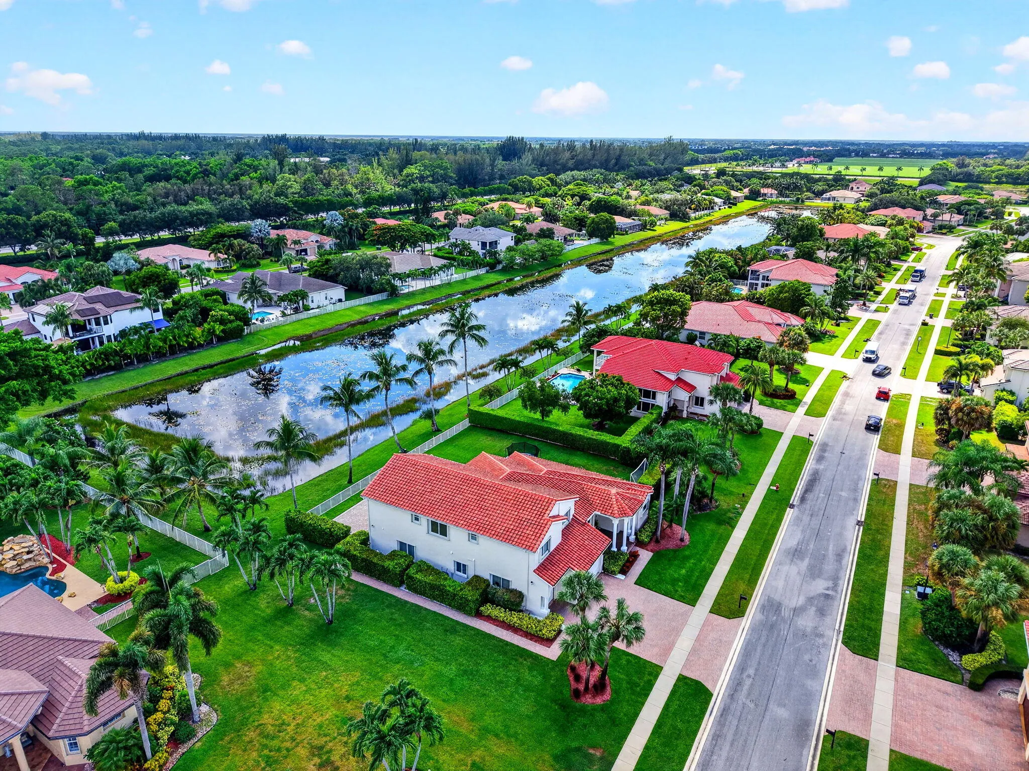 Residential neighborhood featuring properties with red tile roofs, a canal, and mature landscaping