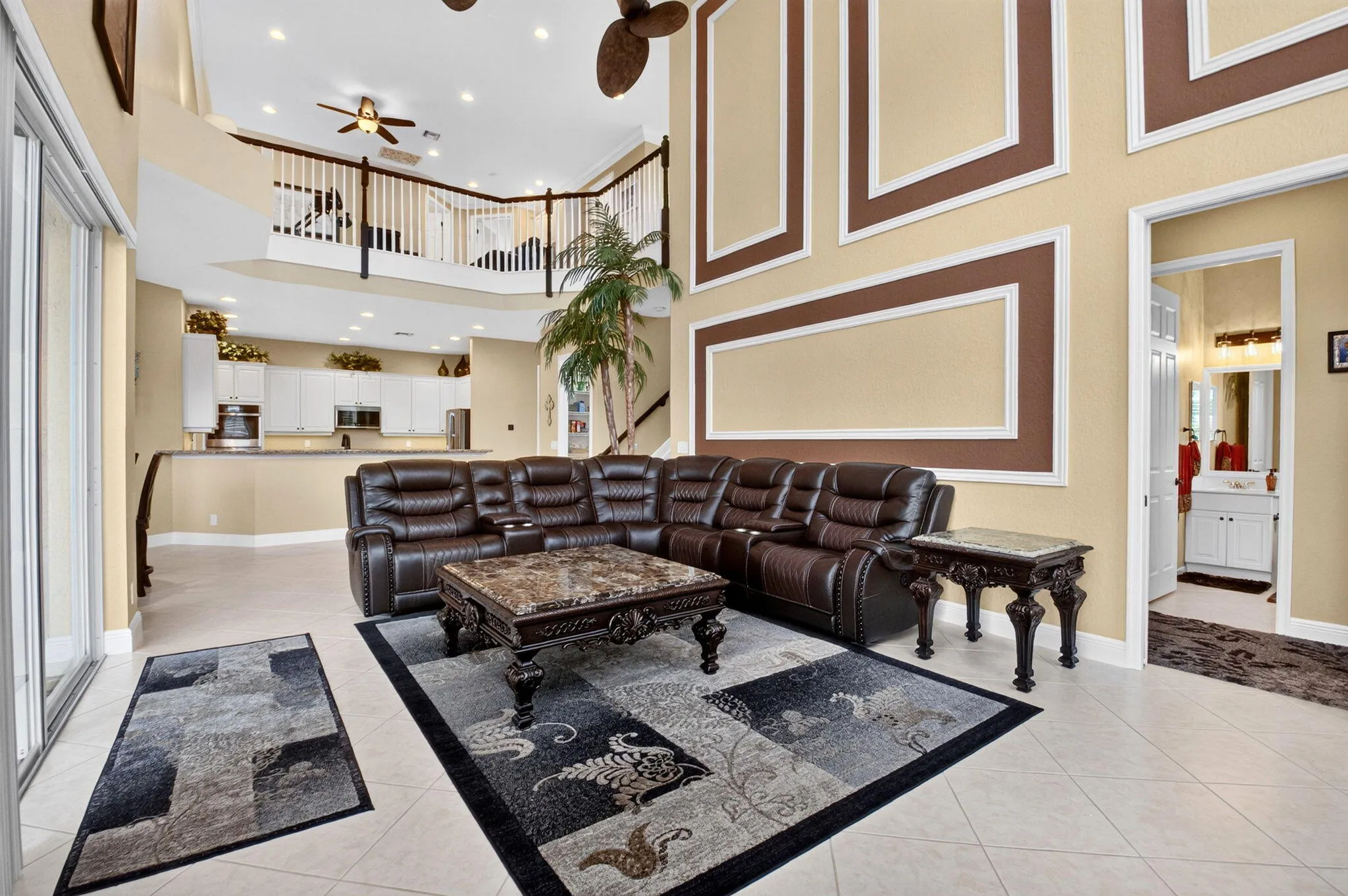 Vaulted ceilings with decorative wall molding, tile flooring, and a kitchen with white cabinetry and stainless steel appliances