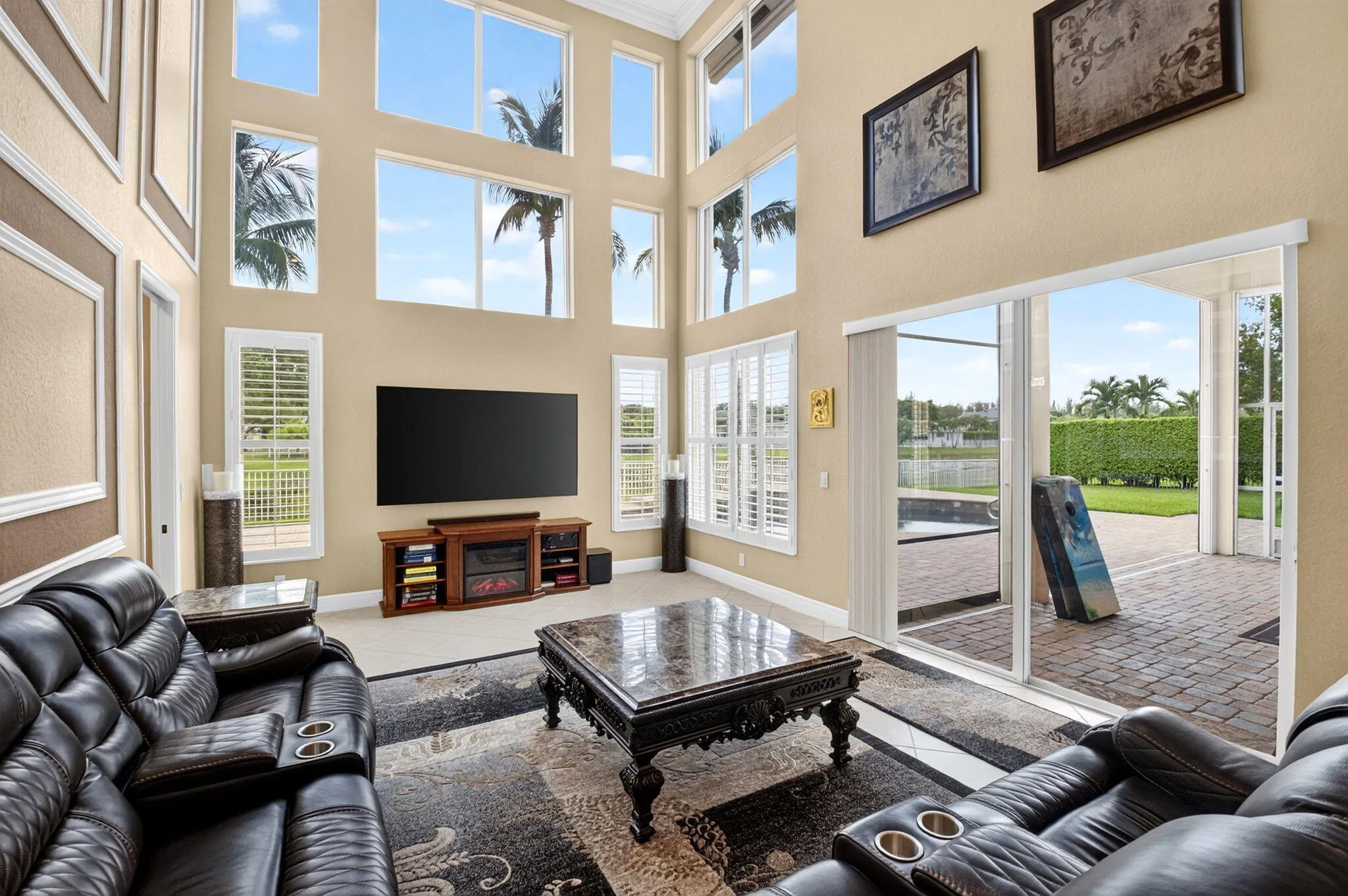 Two-story living area with expansive windows, and direct access to an outdoor patio