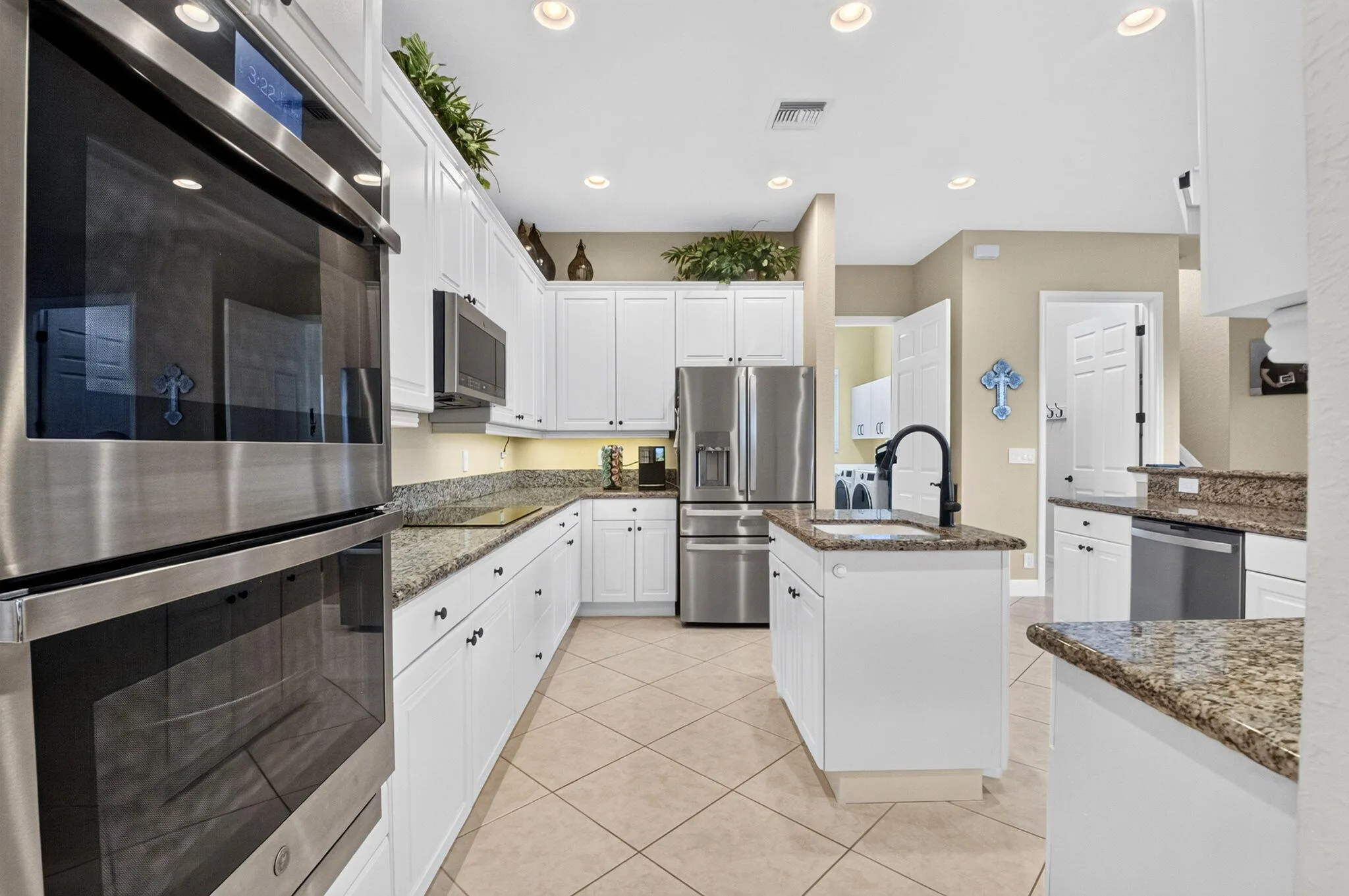White shaker cabinetry, stainless steel appliances, granite countertops, tile flooring, and recessed lighting