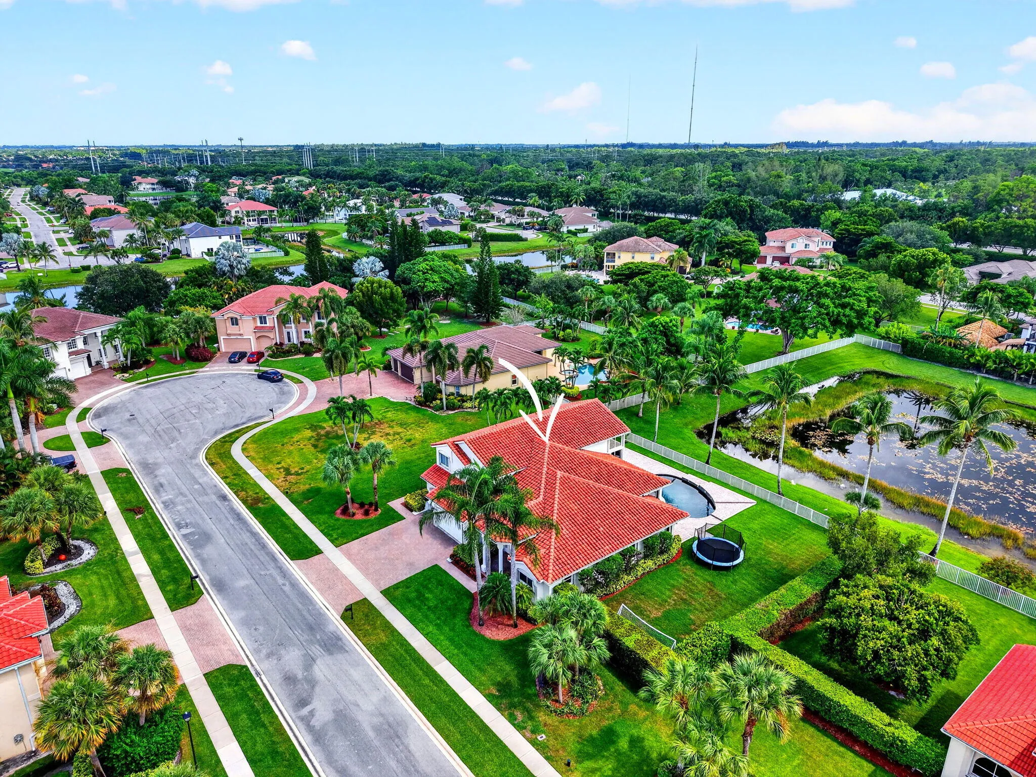 Property featuring a red tile roof, private swimming pool, and a manicured lawn with mature landscaping