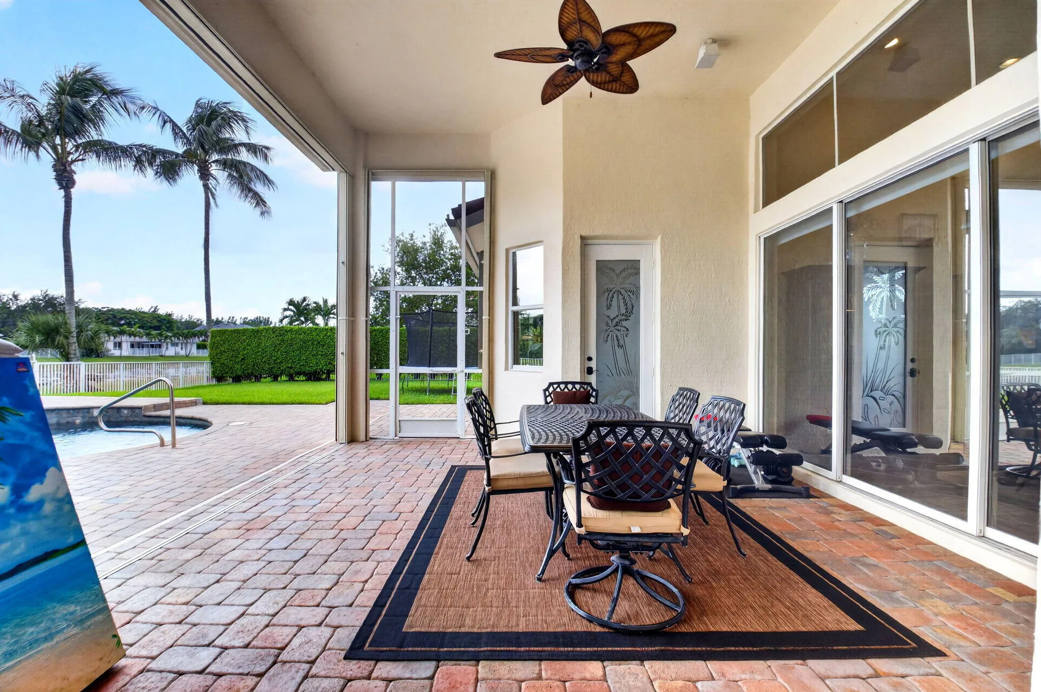 Expansive outdoor patio featuring brick pavers, a built-in pool, and a ceiling fan