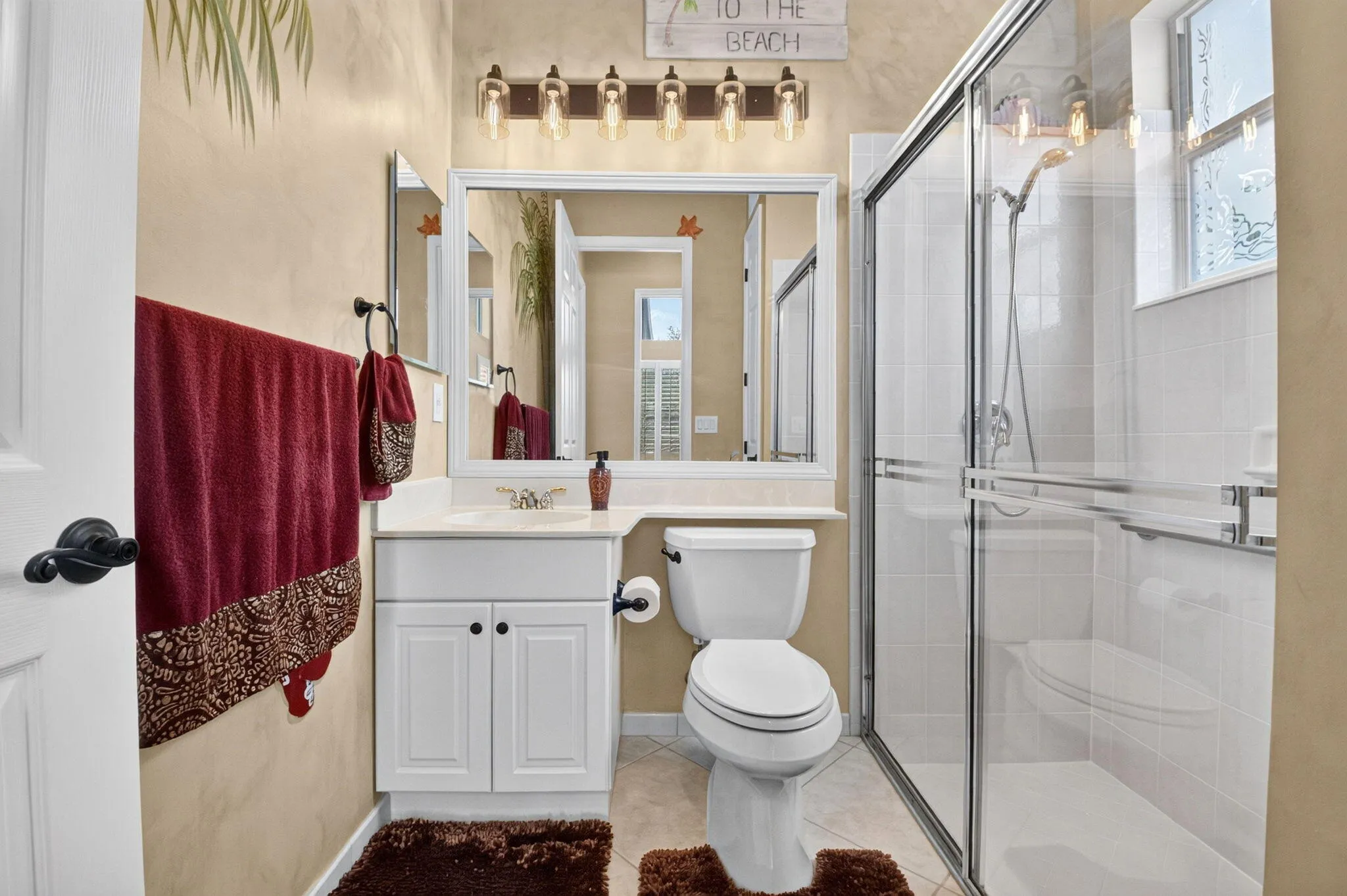 White vanity with a single basin sink, framed mirror, and a multi-bulb light fixture