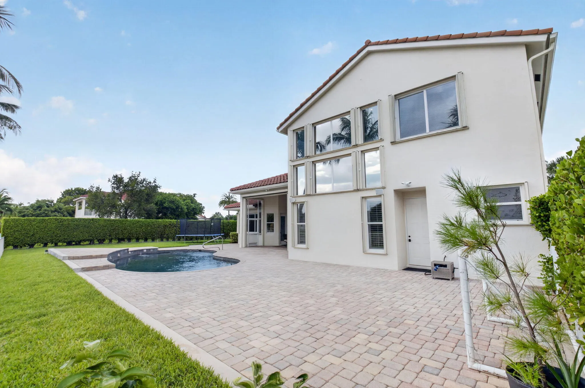 Exterior featuring a tile roof, a swimming pool, paved patio, and a manicured lawn