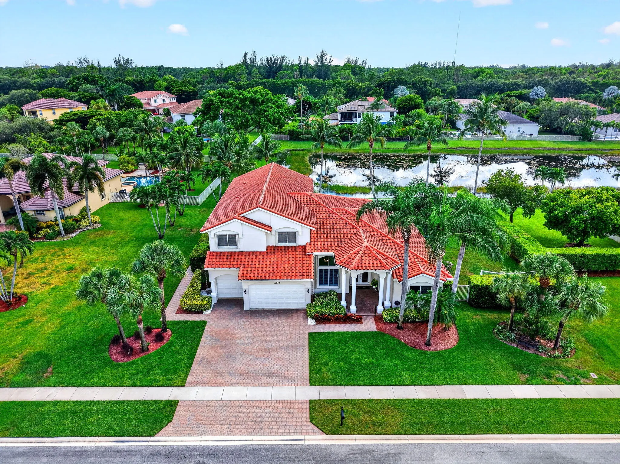 Mediterranean-style residence with a terracotta tile roof, paver driveway, and an attached two-car garage