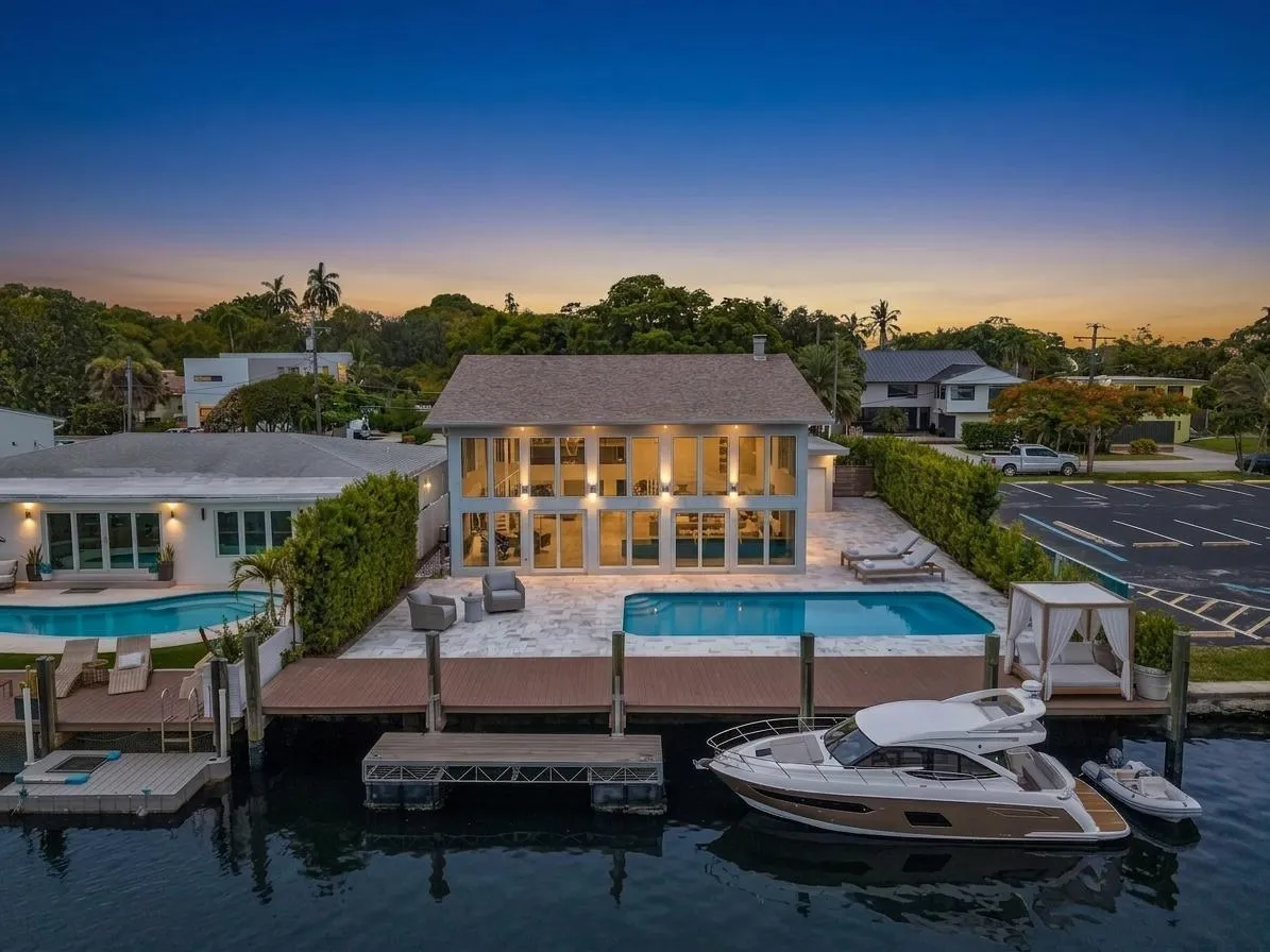 Back of home at twilight with vast pool and waterfront access. Virtually Staged