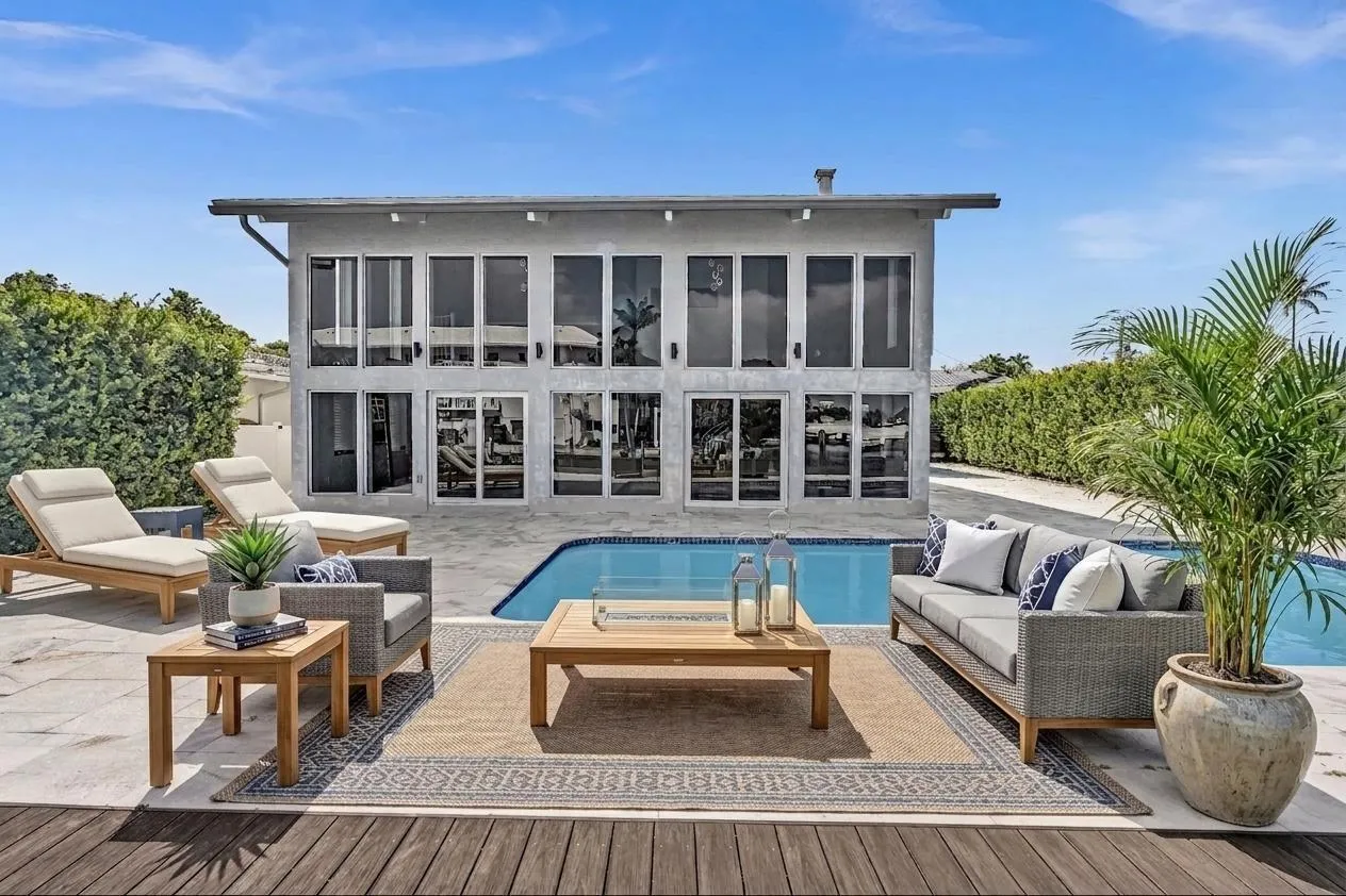 Back of home with lounge chaises and patio furniture. Virtually Staged