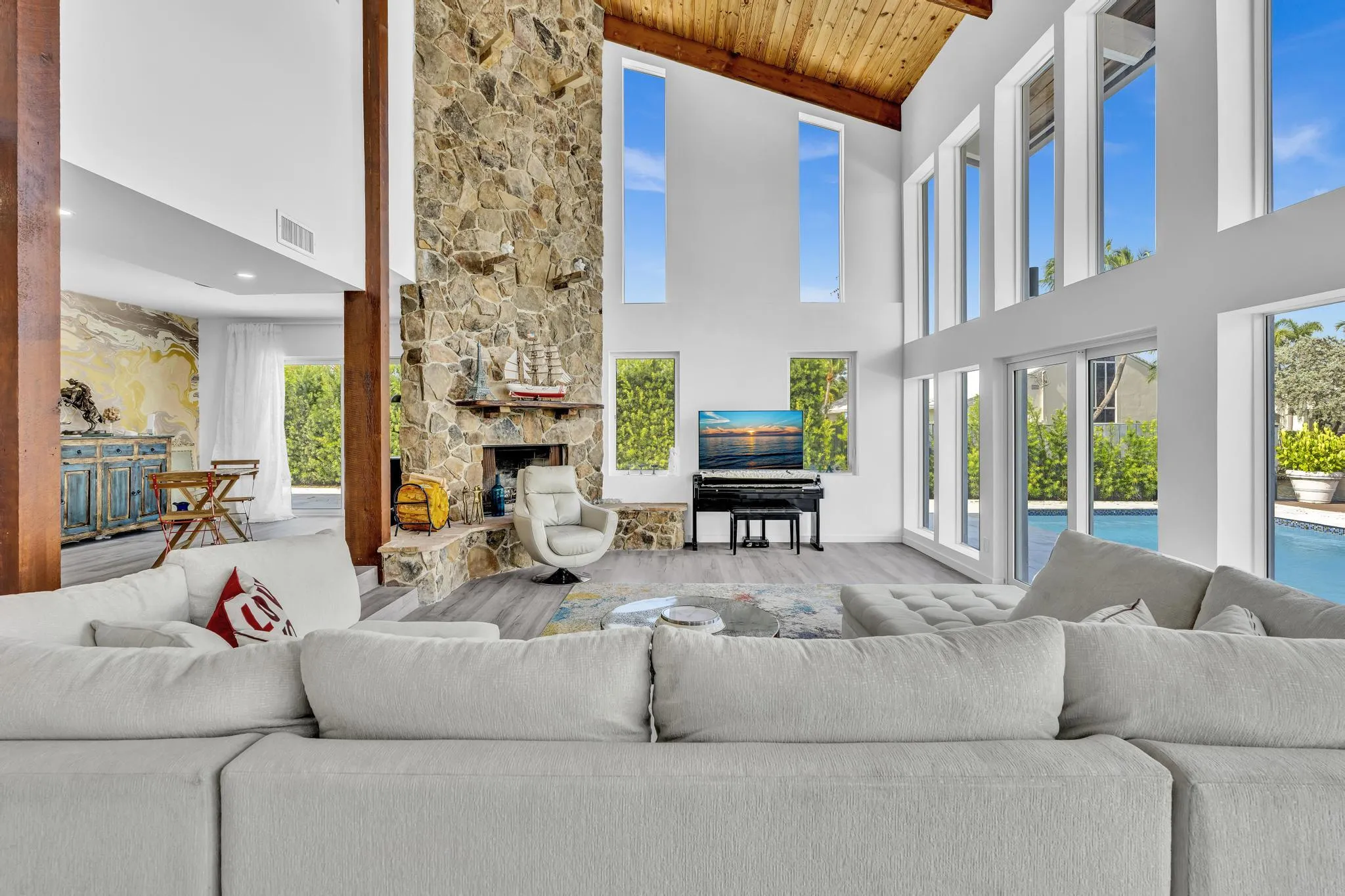 Vaulted ceiling living room with floor to ceiling windows.