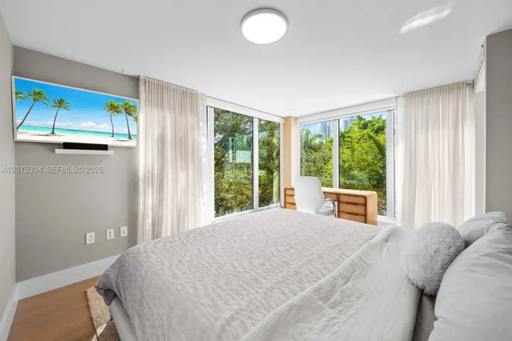 Primary bedroom with large windows, wood floors, and serene ambiance — bright retreat in South of Fifth neighborhood.