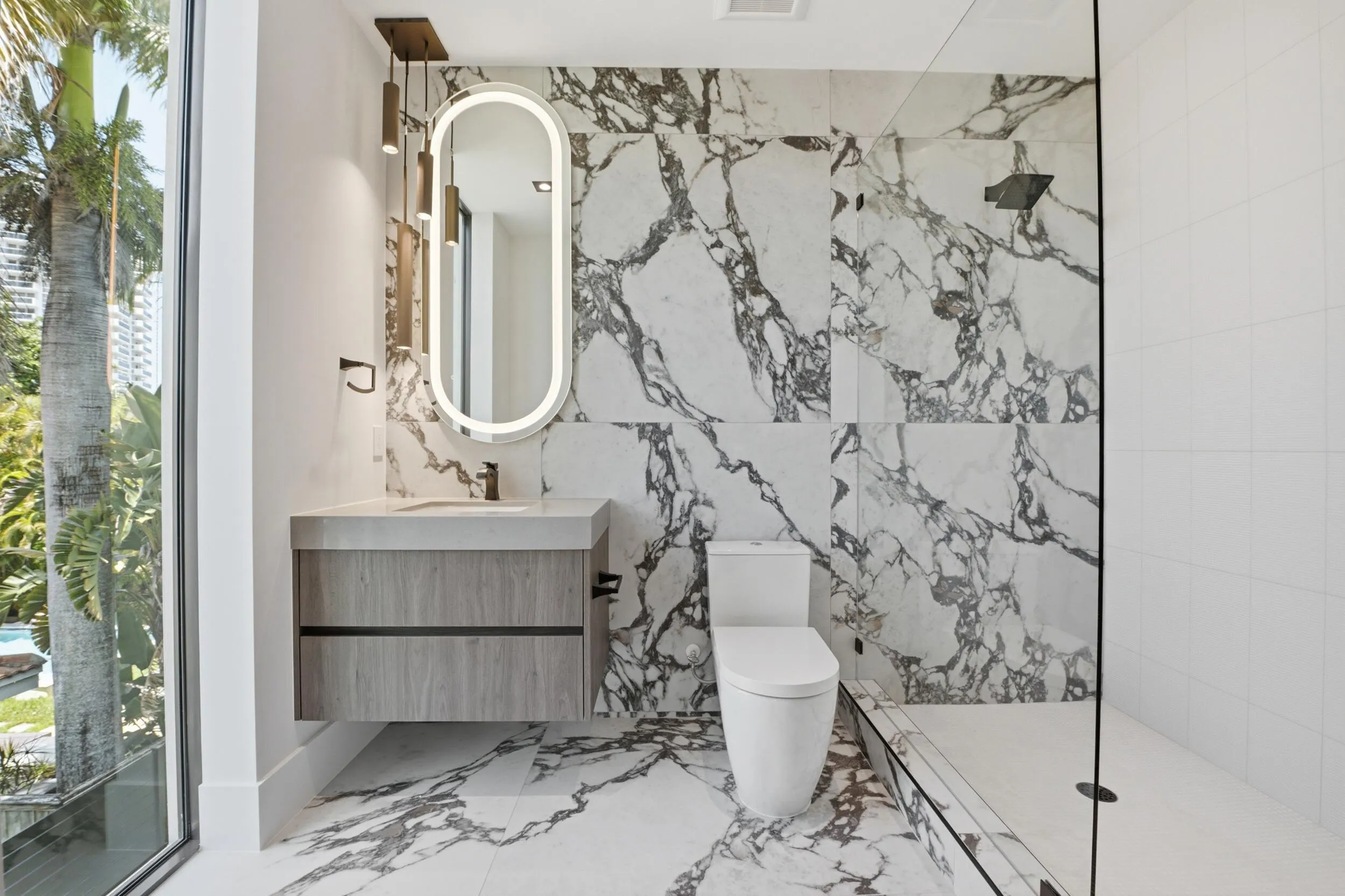 Floating vanity with wood-finish cabinetry, illuminated oval mirror, and a sleek rectangular sink