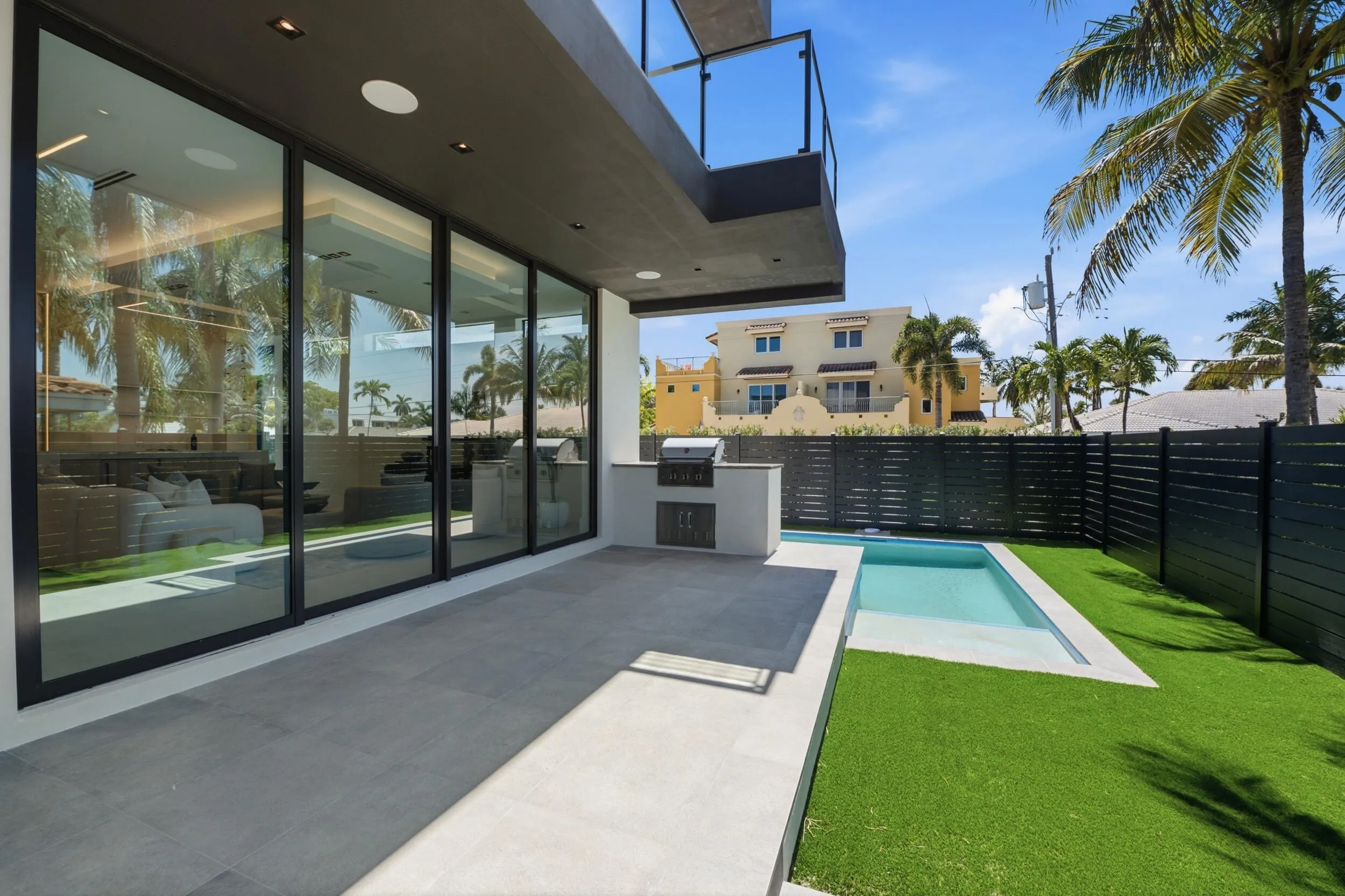 Contemporary architecture featuring a white and dark facade, multiple balconies with glass railings, large windows, an integrated two-car garage, and a paver driveway