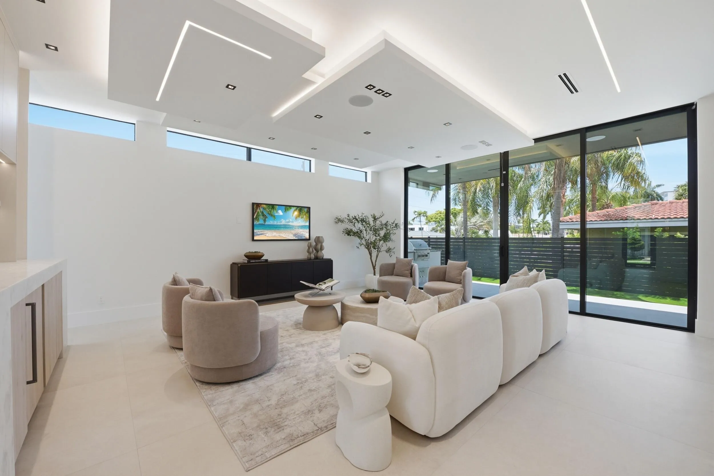 Spacious living area featuring large format tile flooring, recessed and linear ceiling lighting, transom windows, and full-height glass doors