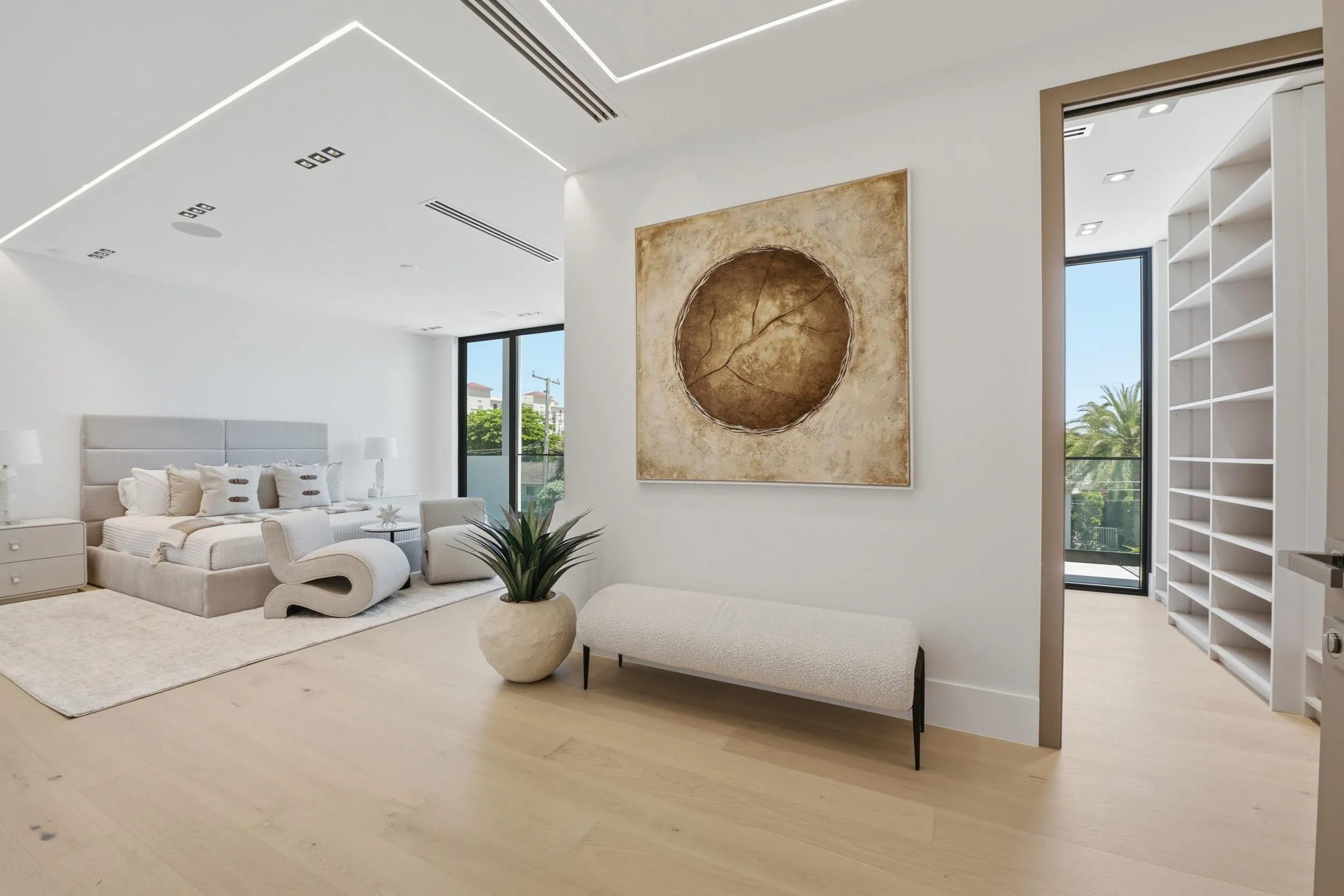 Light wood-finish flooring with recessed ceiling lighting, a built-in wall of shelving, full-height windows, and a patio door