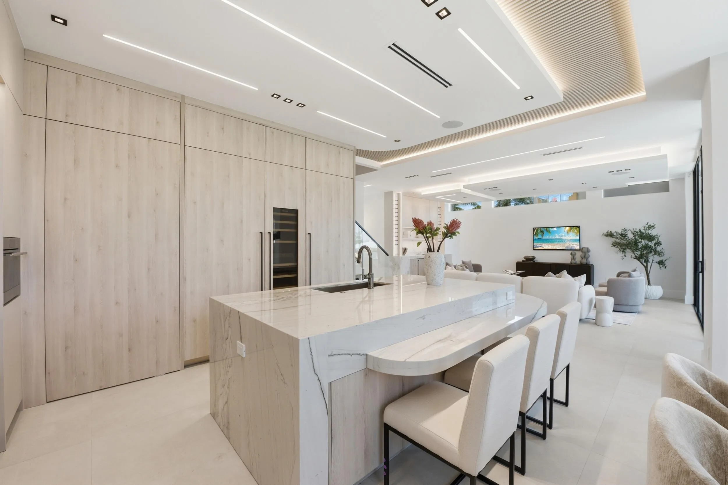Kitchen featuring integrated appliances, a waterfall island with an eating bar, recessed lighting, and light wood-finish cabinetry