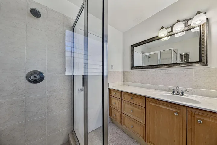 Bathroom features a tiled glass-enclosed shower, substantial vanity storage and generous counter space.