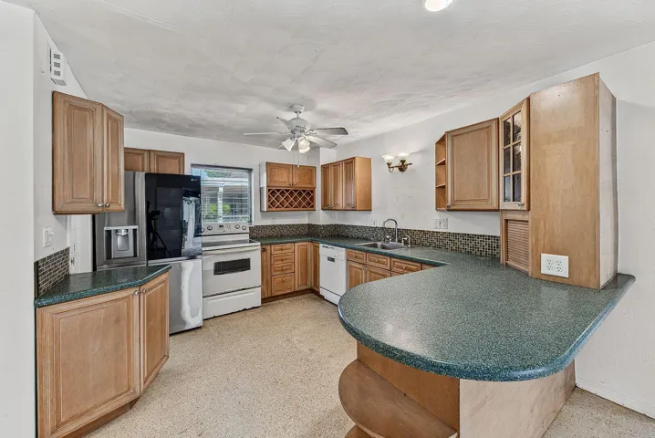 Large kitchen with abundant cabinetry, extensive counter space and a curved breakfast bar.