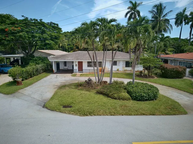 Single-story residence with a circular driveway, mature palms and convenient covered entry.