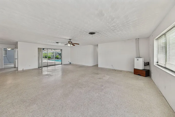 Generously proportioned living space with terrazzo flooring and direct access to the screened pool area.