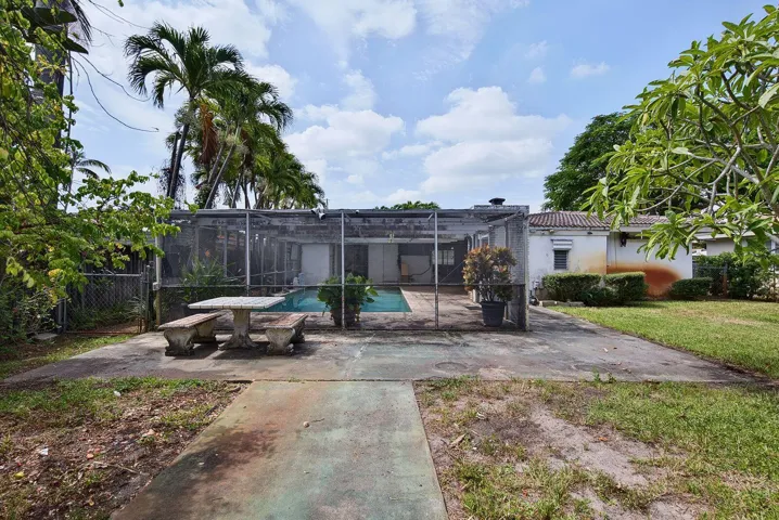 Wide view of the screened swimming pool, surrounding patio and expansive yard beyond.