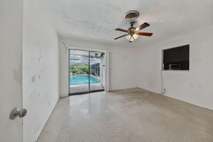 Spacious bedroom with terrazzo flooring and sliding-glass doors opening directly to the pool area.