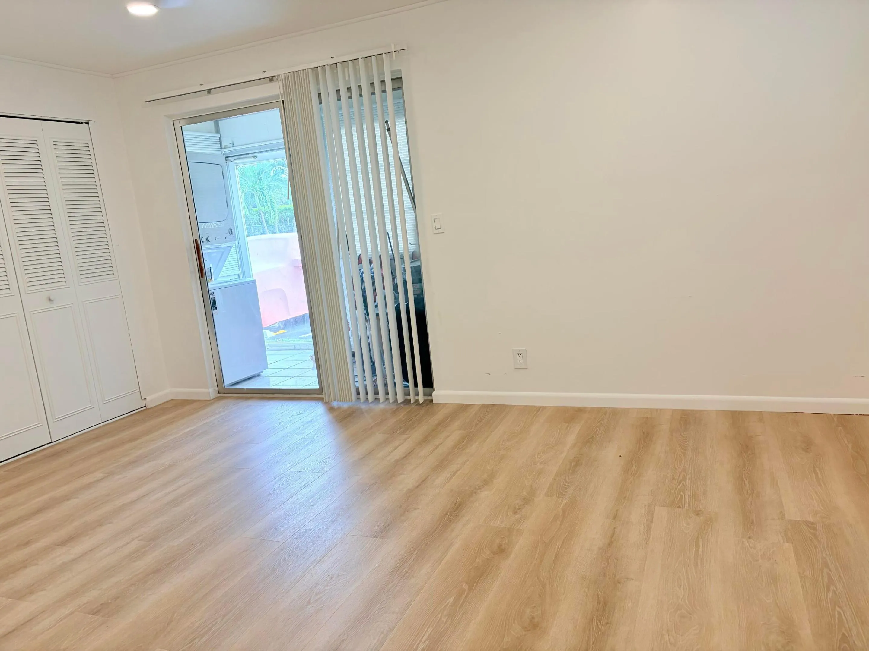 Wood-finish flooring, white bi-fold closet doors, sliding glass door, vertical blinds, and a ceiling fan