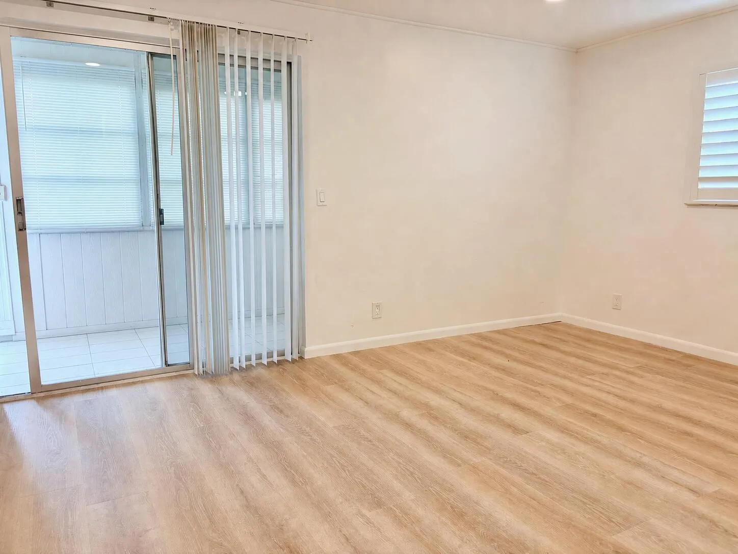 Wood-finish flooring, white walls, and a sliding glass door to an enclosed outdoor area