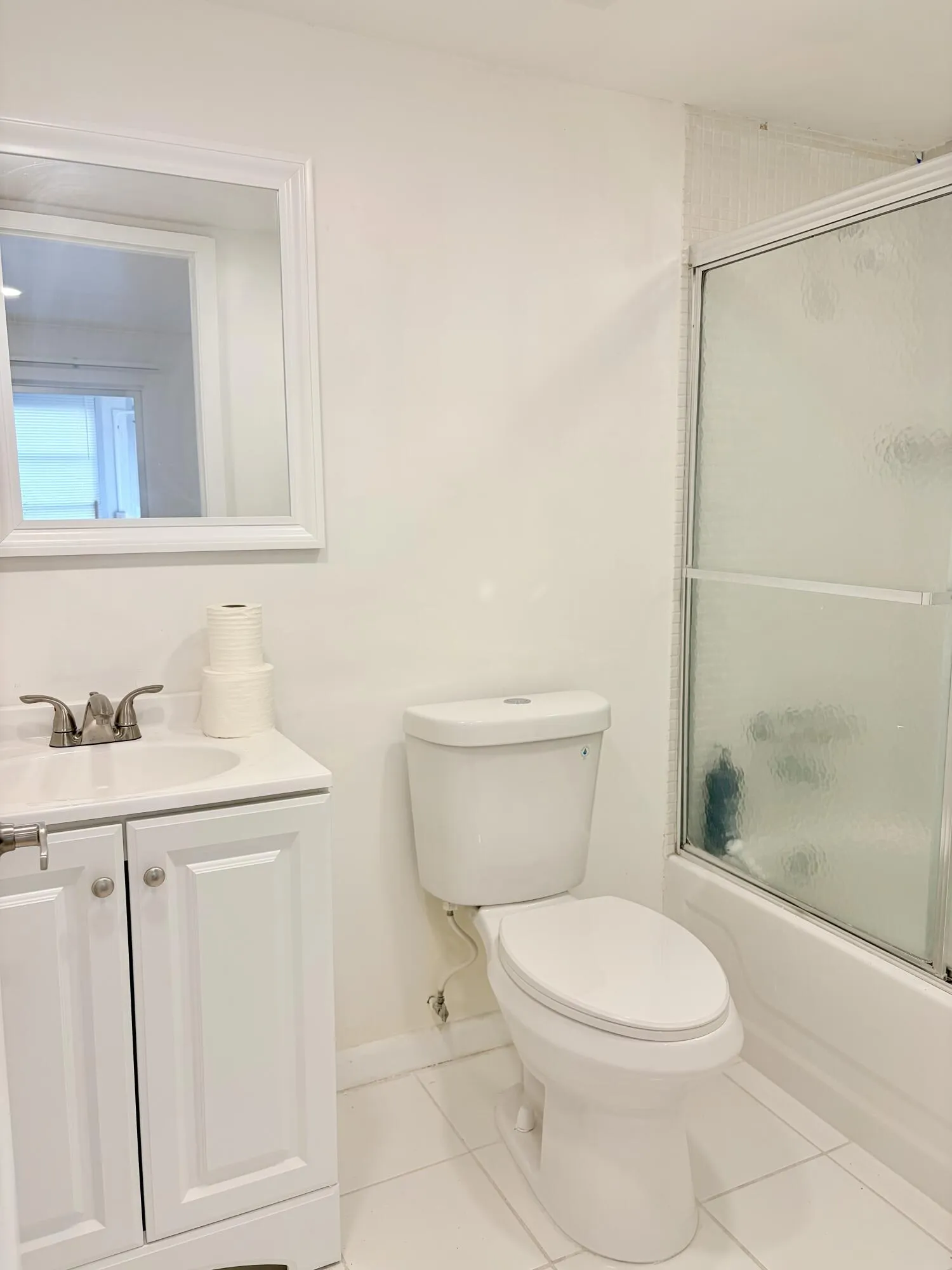 Bathroom featuring white cabinetry, a ceramic vanity sink with a chrome faucet, a white toilet, and a shower with sliding glass doors