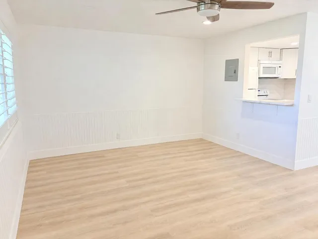 Recessed lighting, ceiling fan with wood-finish blades, wood-finish flooring, wainscoting, and a pass-through kitchen opening