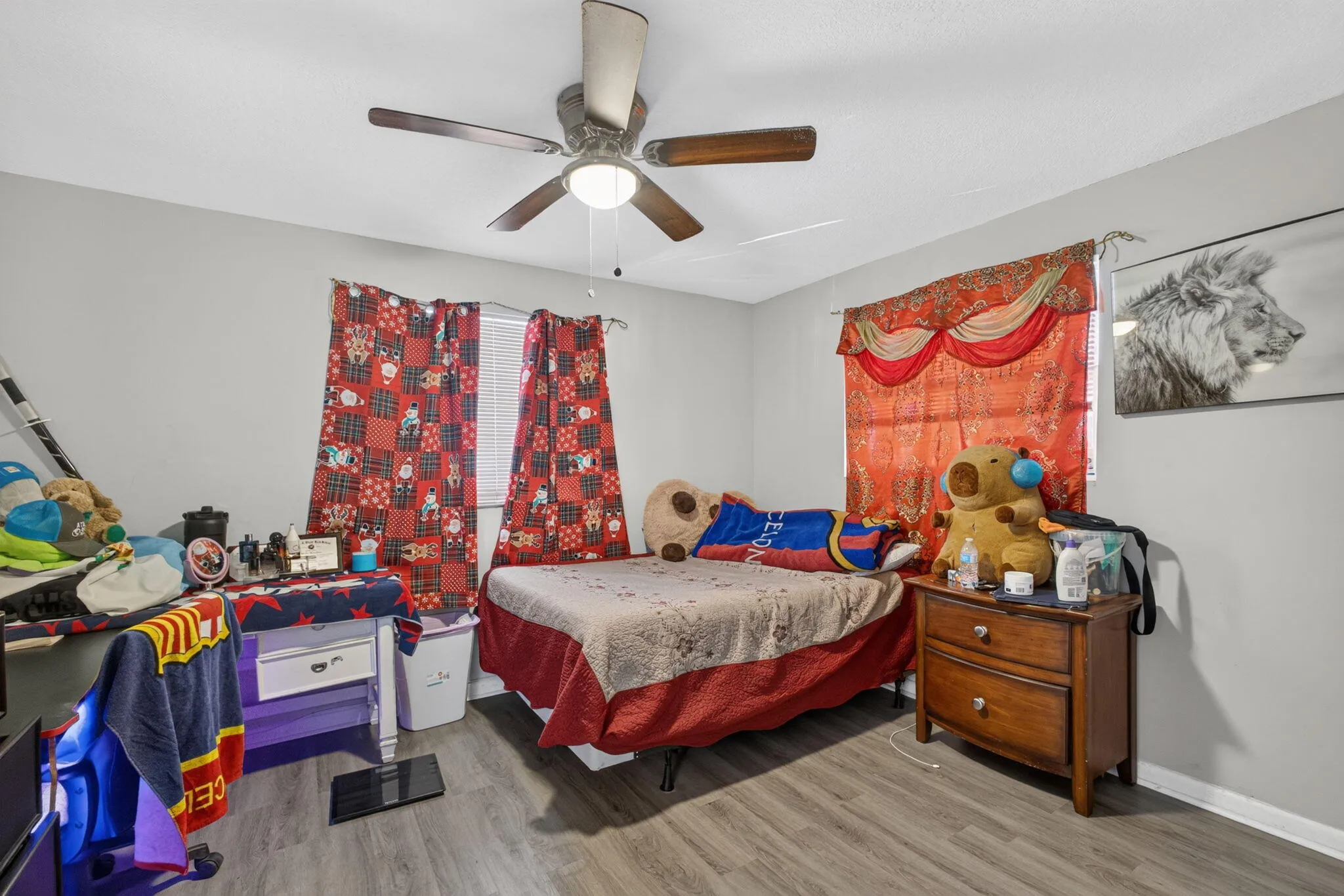 Gray wall paint, ceiling fan with light, wood-finish flooring, and window with blinds