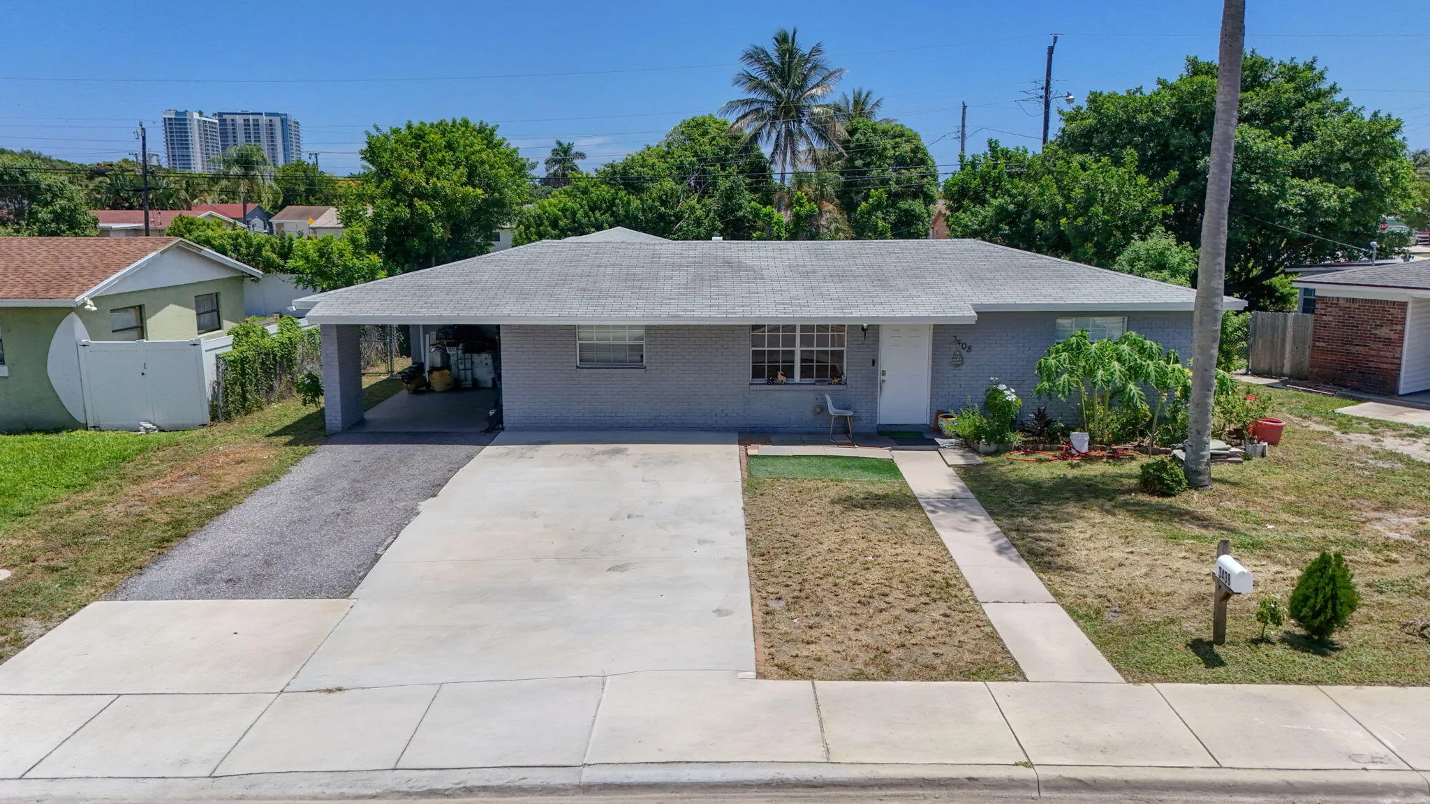 Single-story residence featuring a shingle roof, carport, concrete driveway, and a paved walkway