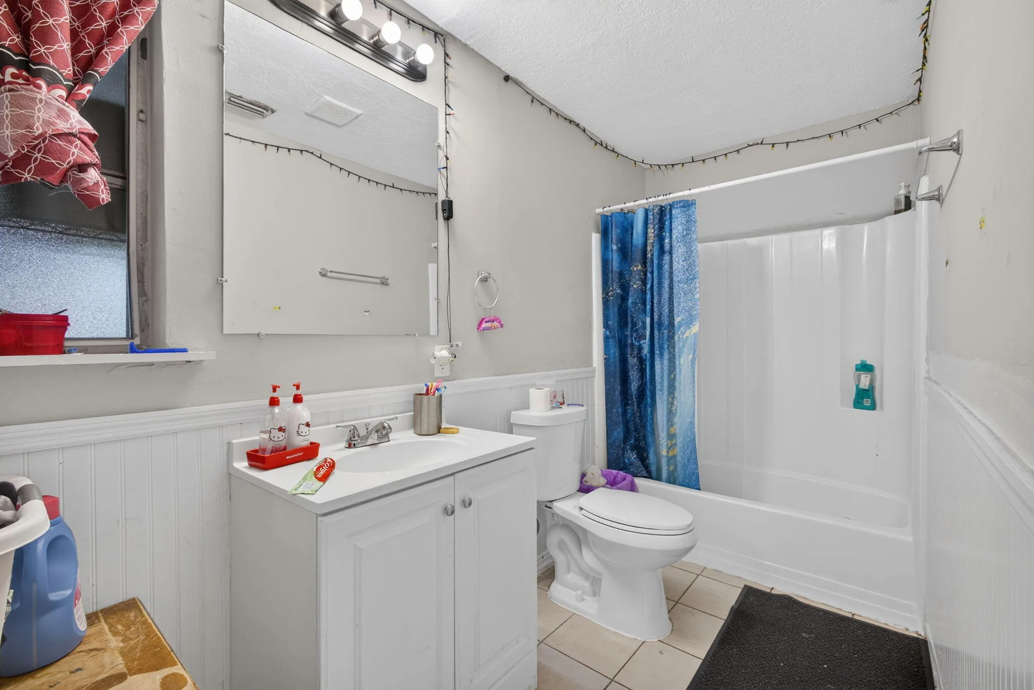 White vanity with integrated sink, wall-mounted mirror, and overhead strip lighting