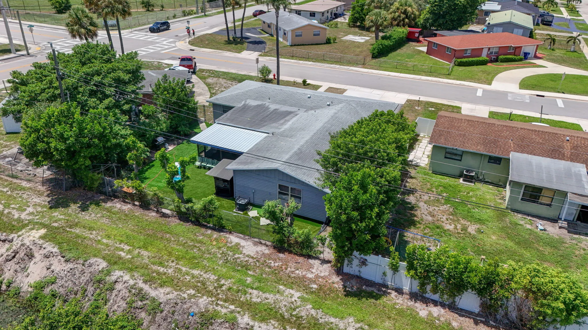 Fenced backyard with established trees, and a screened patio