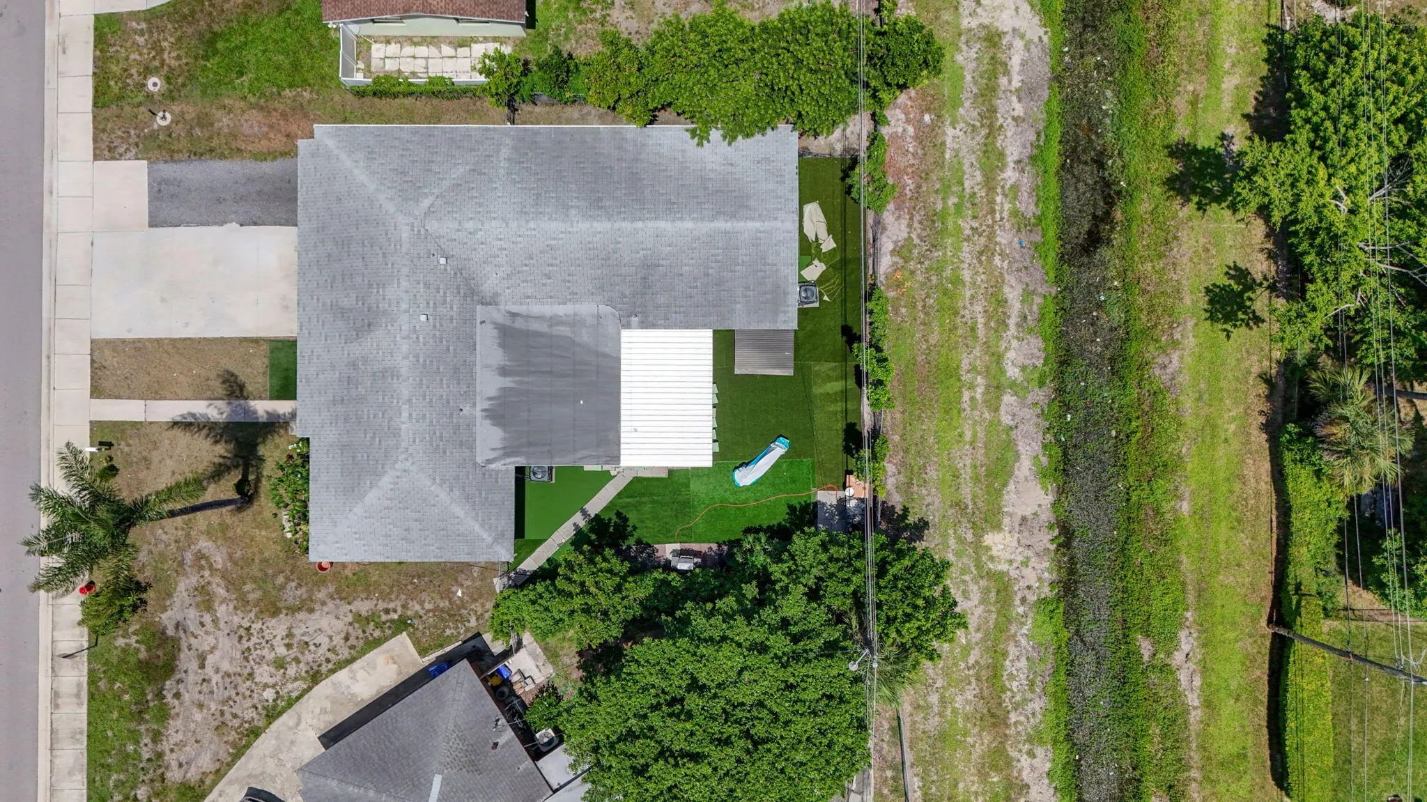 Property featuring a multi-gable roof, expansive paved driveway, and established trees