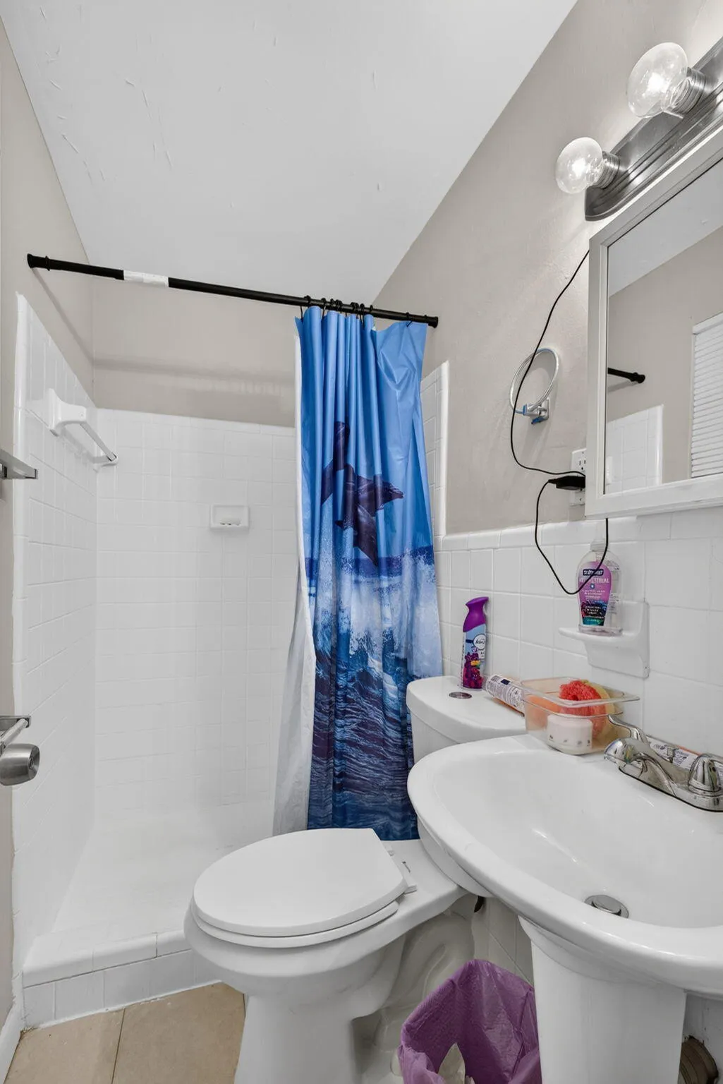 White tiled shower stall, pedestal sink, and toilet