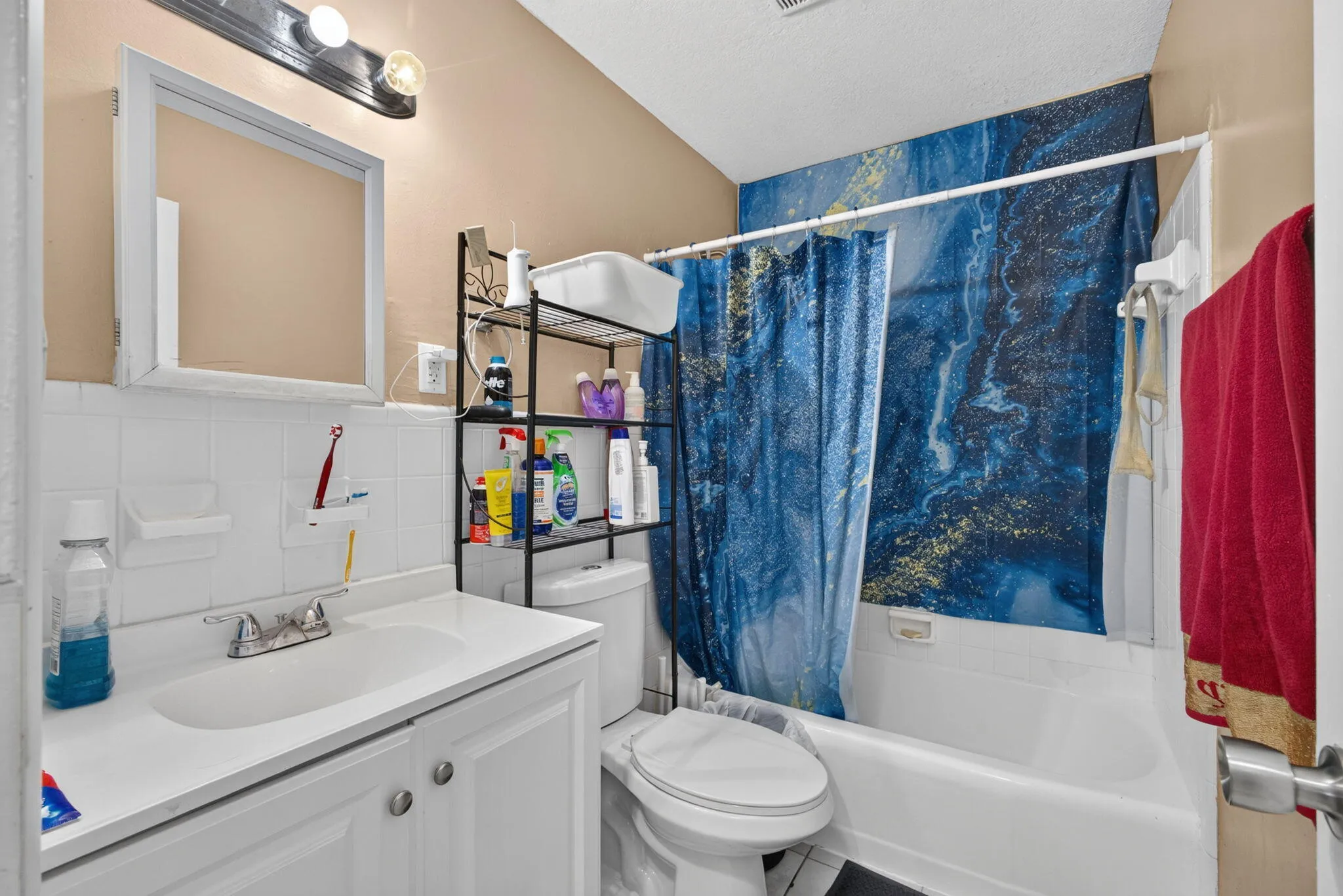 White vanity with integrated sink, chrome faucet, wall-mounted mirror, and tile backsplash
