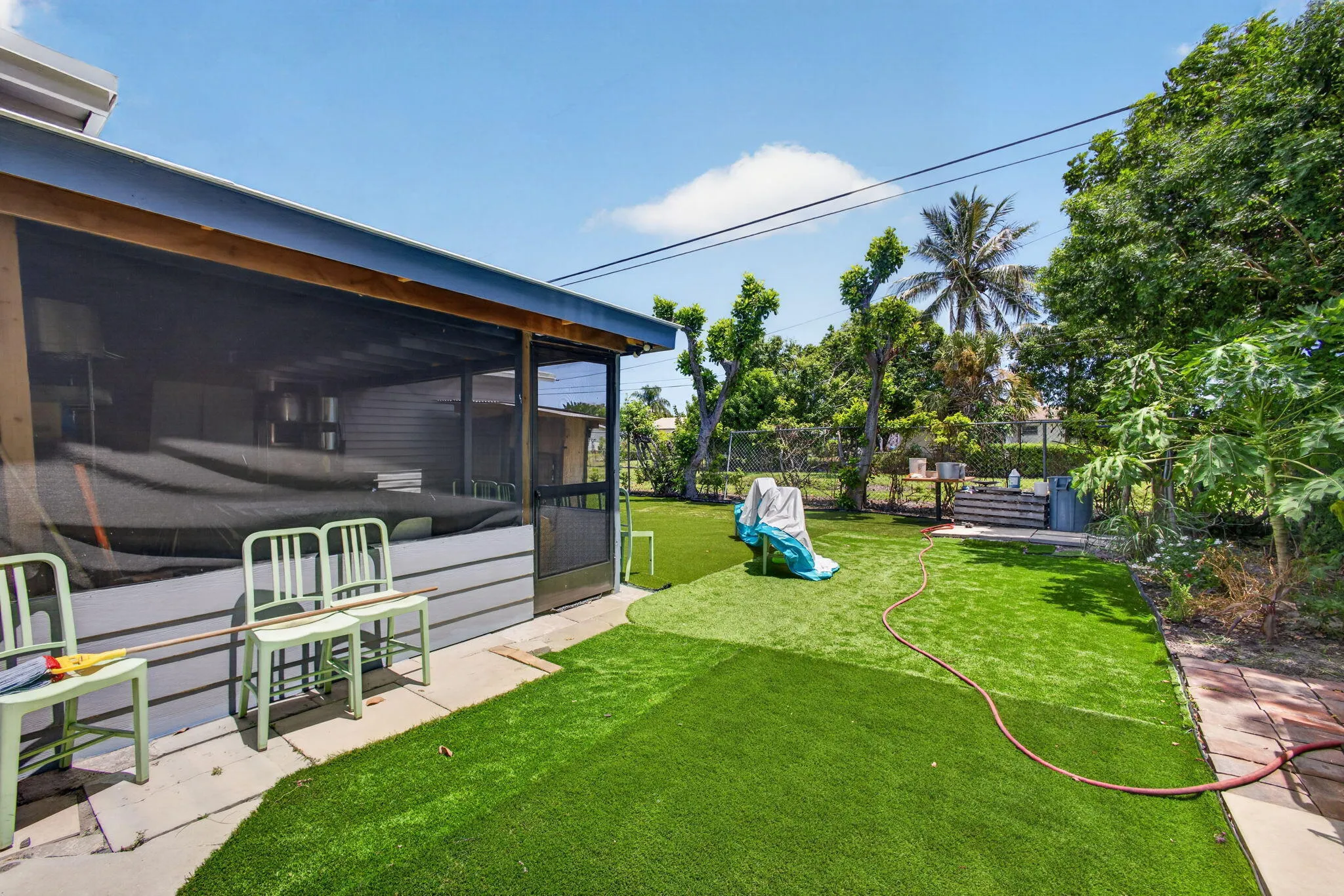 Screened-in patio with direct access to a fenced yard featuring artificial turf