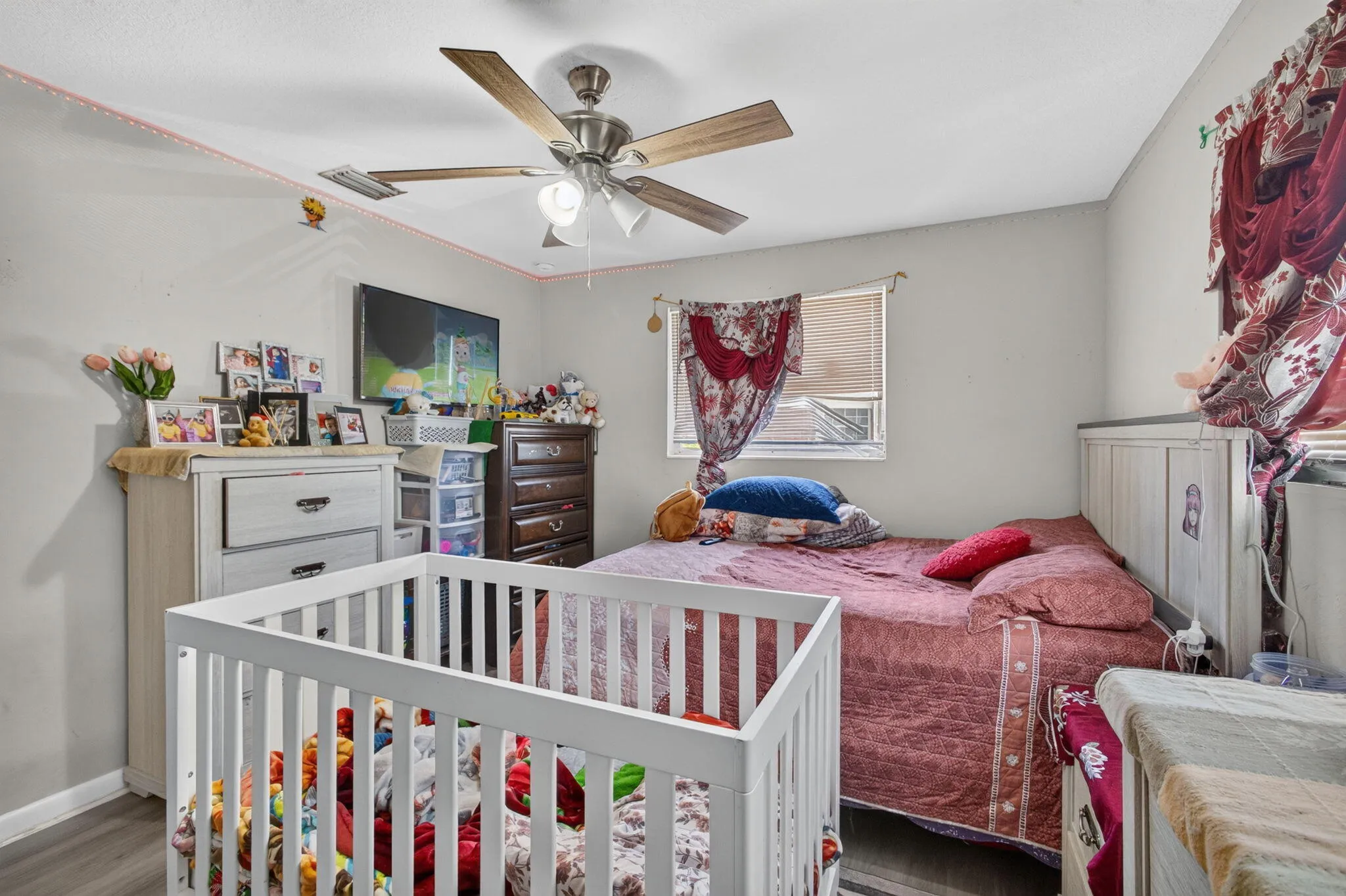 Ceiling fan with integrated lighting, wood-finish flooring, and white walls
