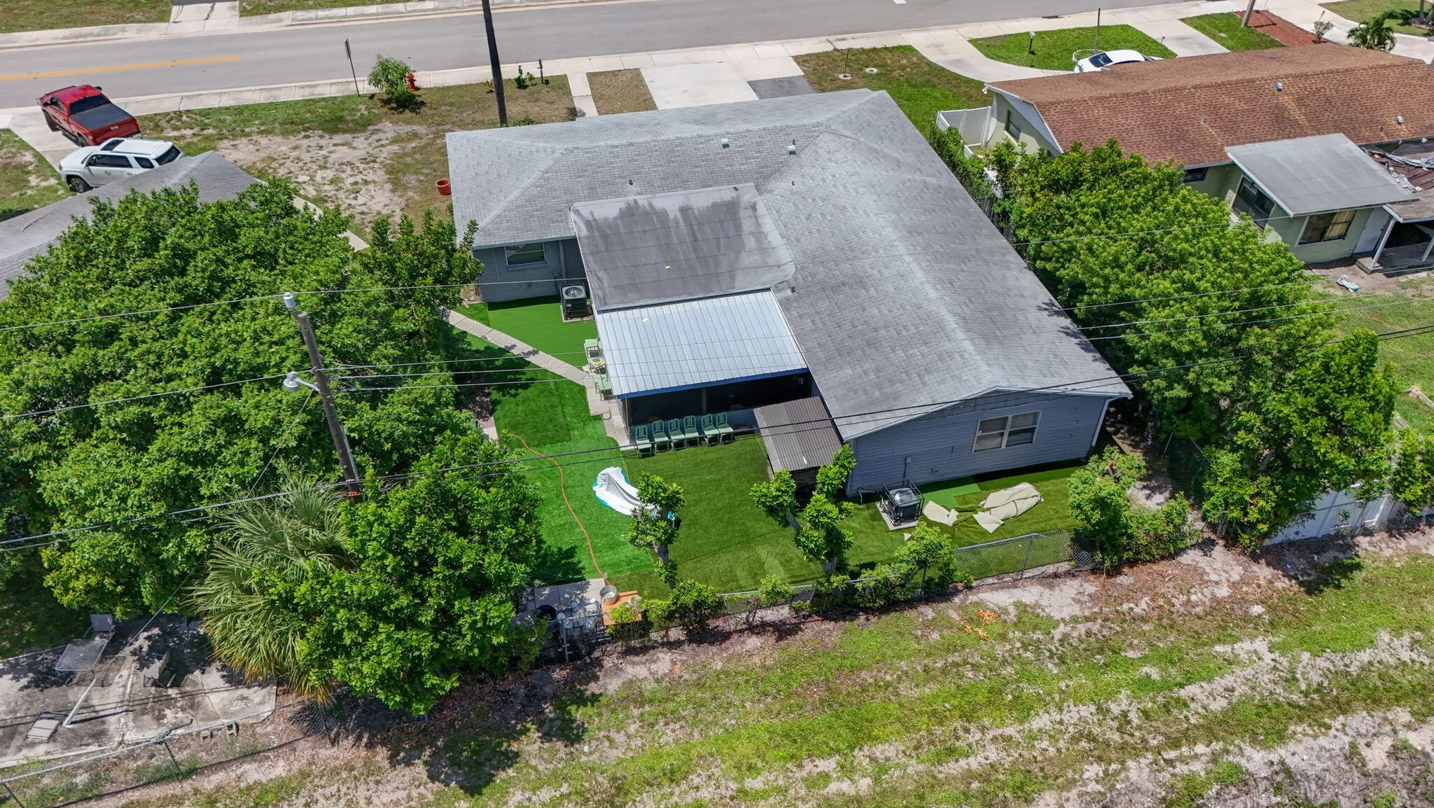 Expansive fenced yard with lush green landscaping, mature trees, and a covered patio structure
