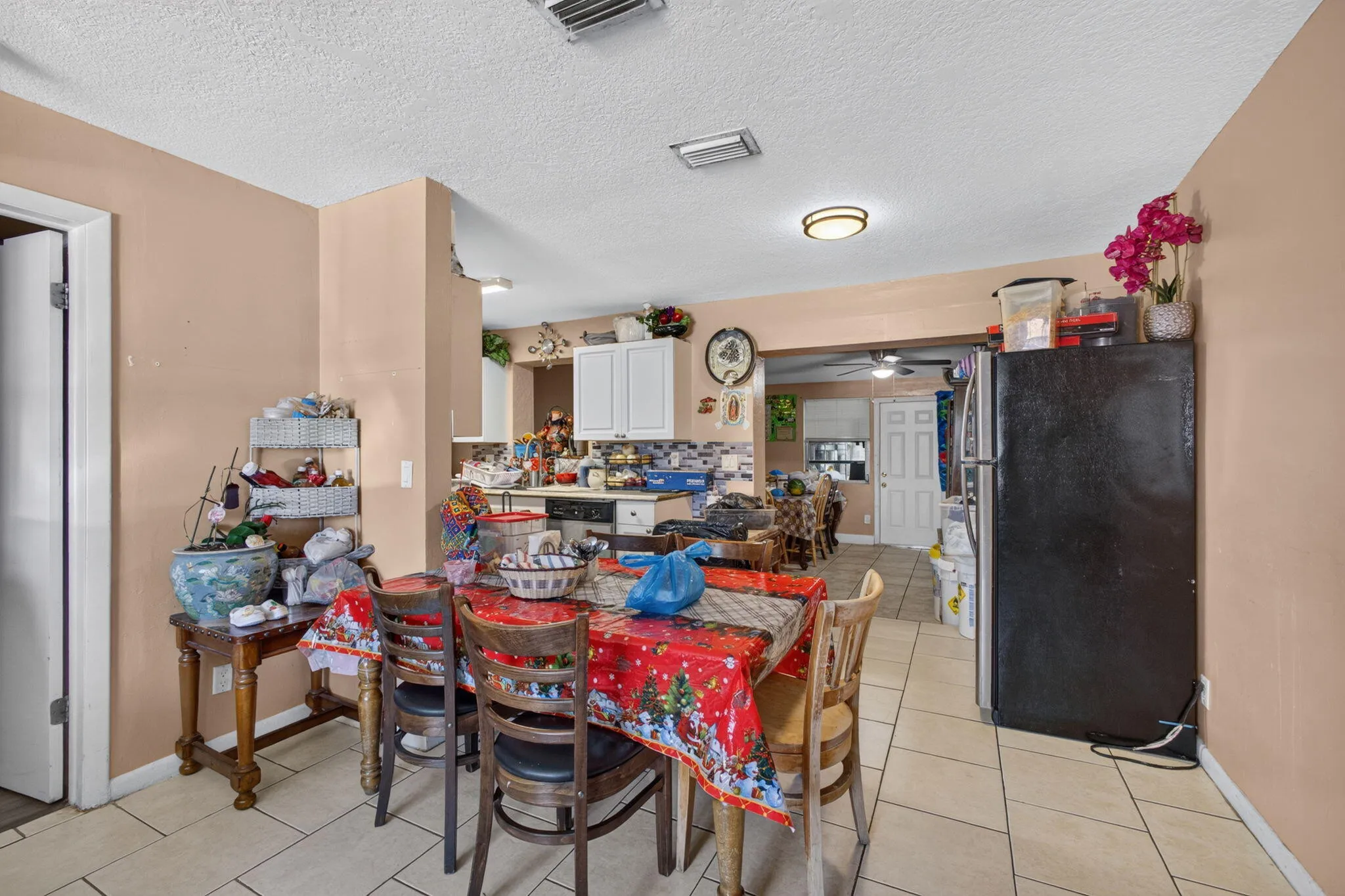 Tile flooring extending throughout, leading to a kitchen with white cabinetry and a black appliance package