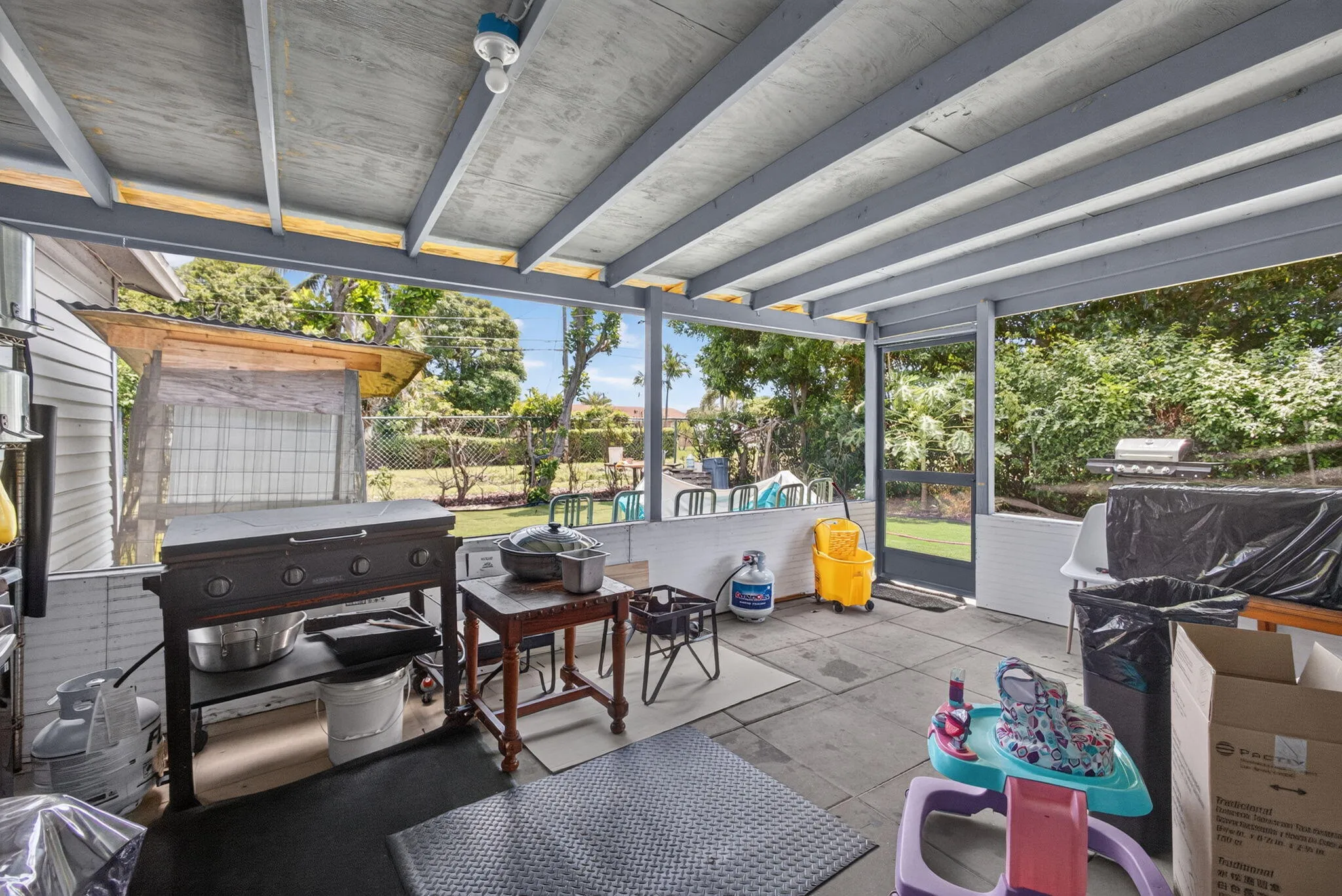 Covered patio with exposed beam ceiling, concrete flooring, and surrounding fencing
