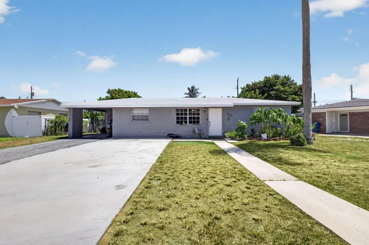 Light gray exterior with white trim, a covered carport, and a concrete driveway