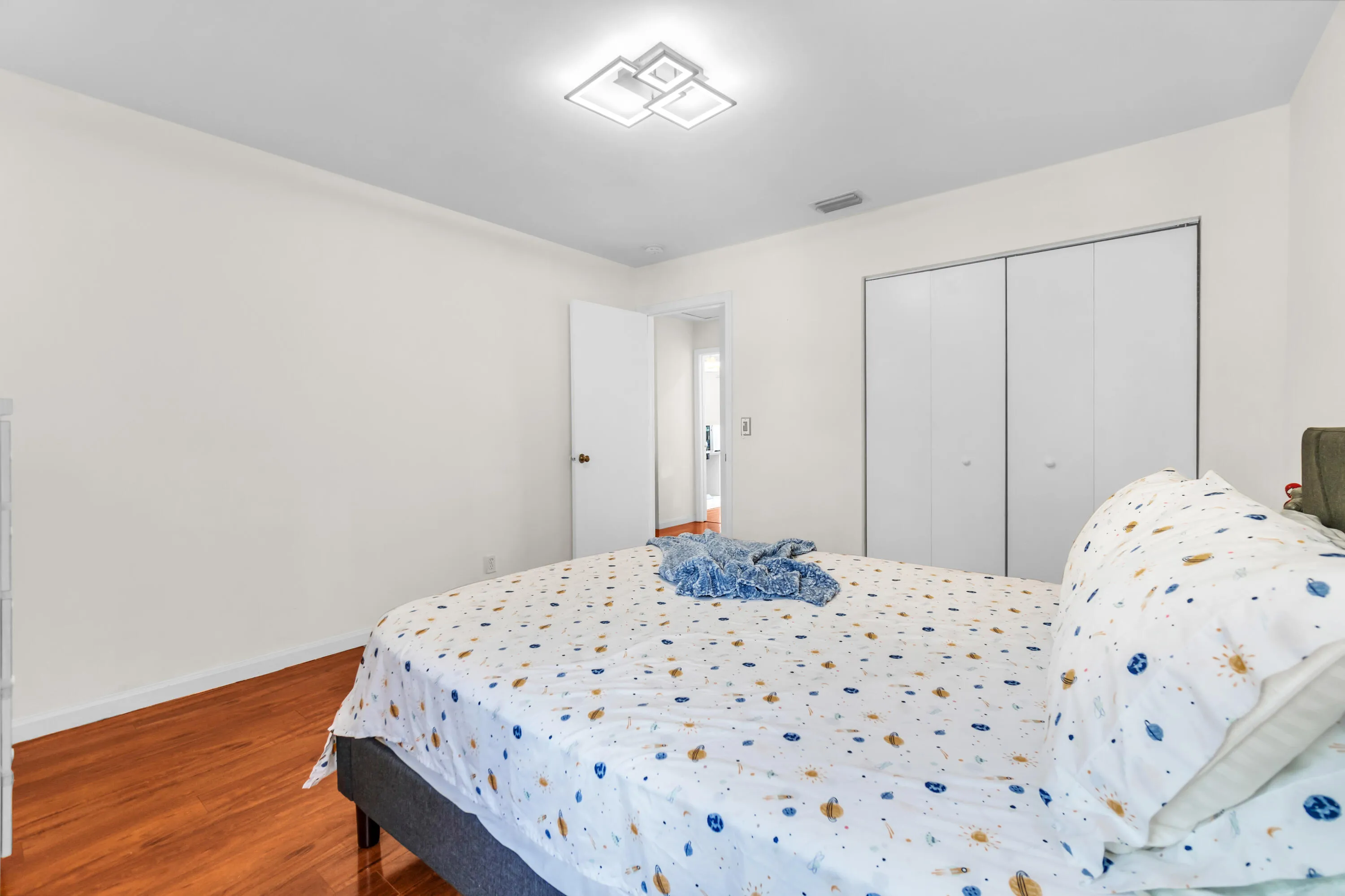 Wood-finish flooring, white walls, and a contemporary ceiling light fixture